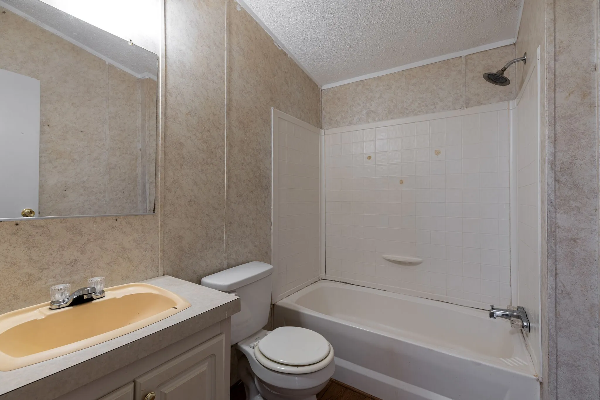 Bathroom featuring a vanity with an integrated sink, a toilet, and a combined shower-tub unit