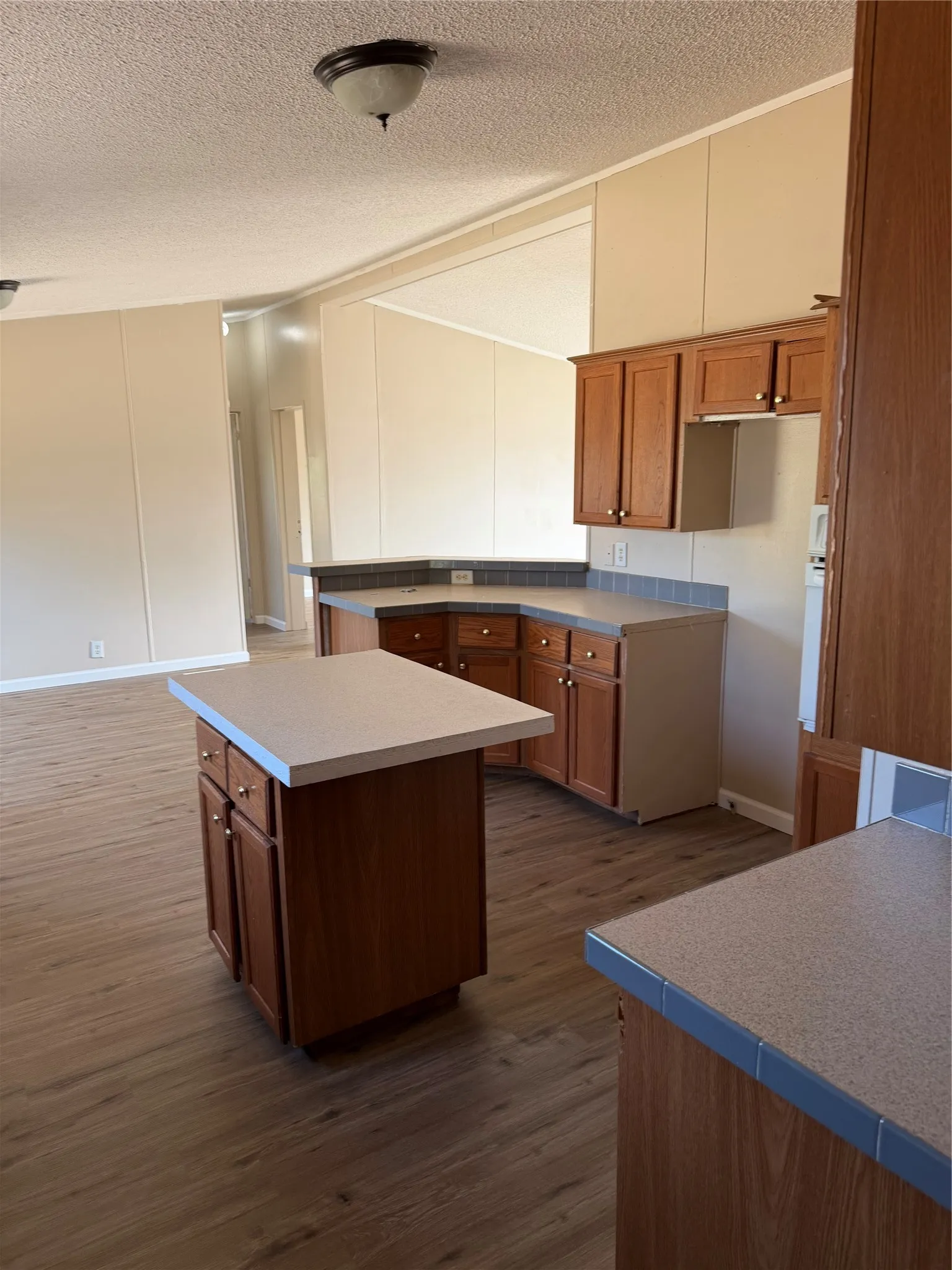 Kitchen featuring wood-finish cabinetry, solid surface countertops, and a central island