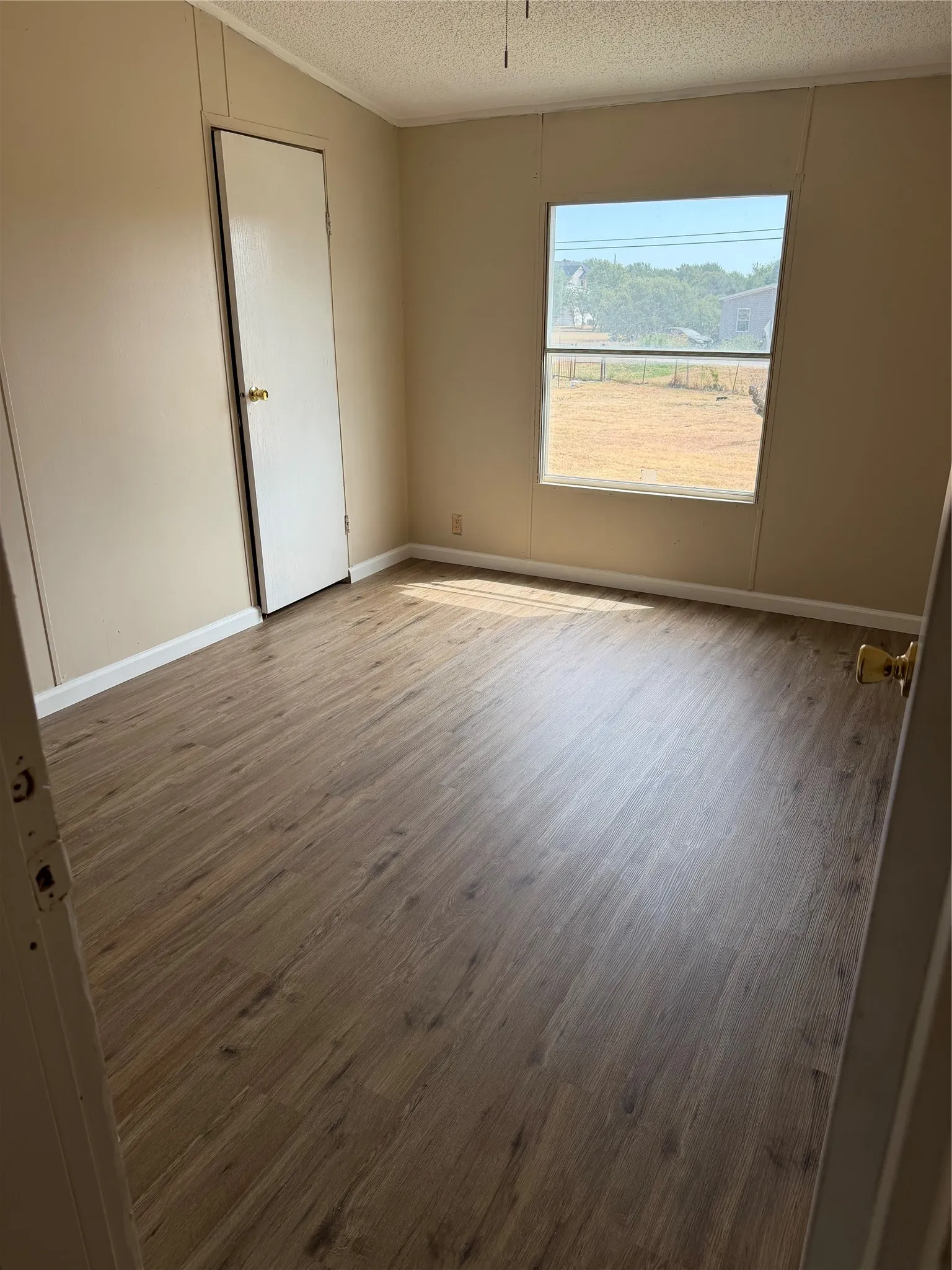 Wood-finish flooring throughout, neutral tone walls, and a single window