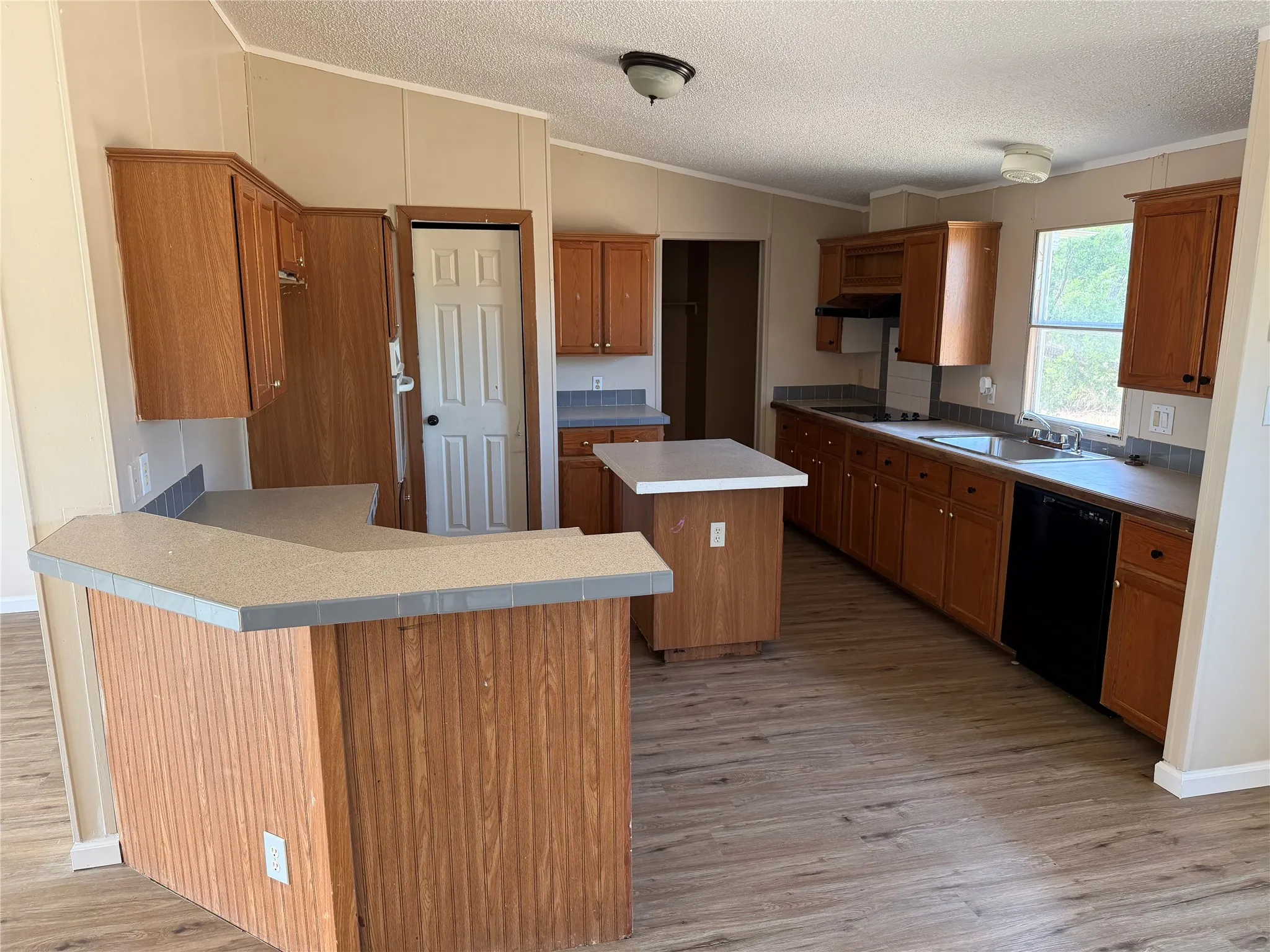 Kitchen featuring wood-finish cabinetry, a central island, a breakfast bar, wood-finish flooring, and a stainless steel sink