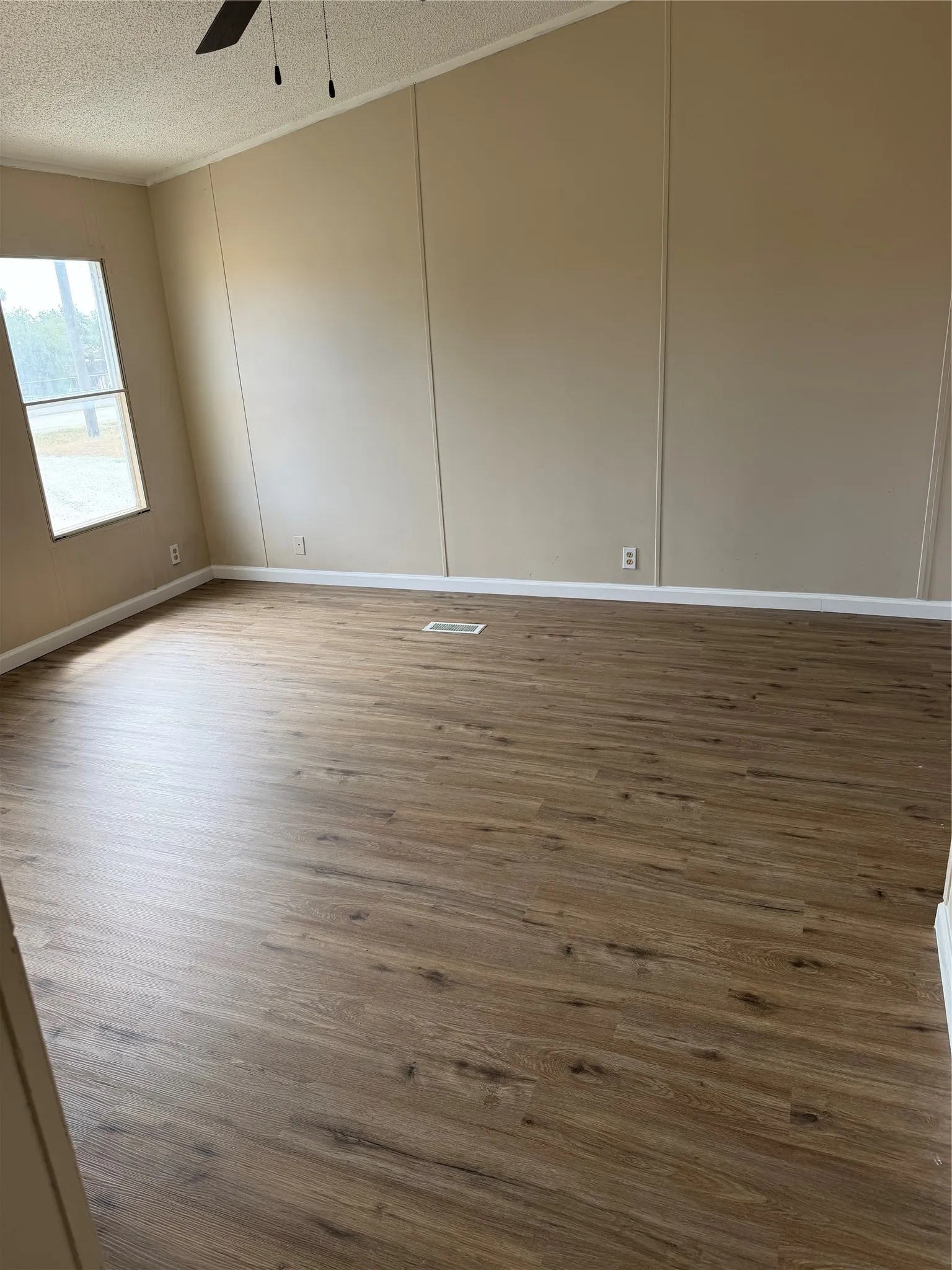 Wood-finish flooring with neutral wall paneling, vaulted ceiling, and a ceiling fan