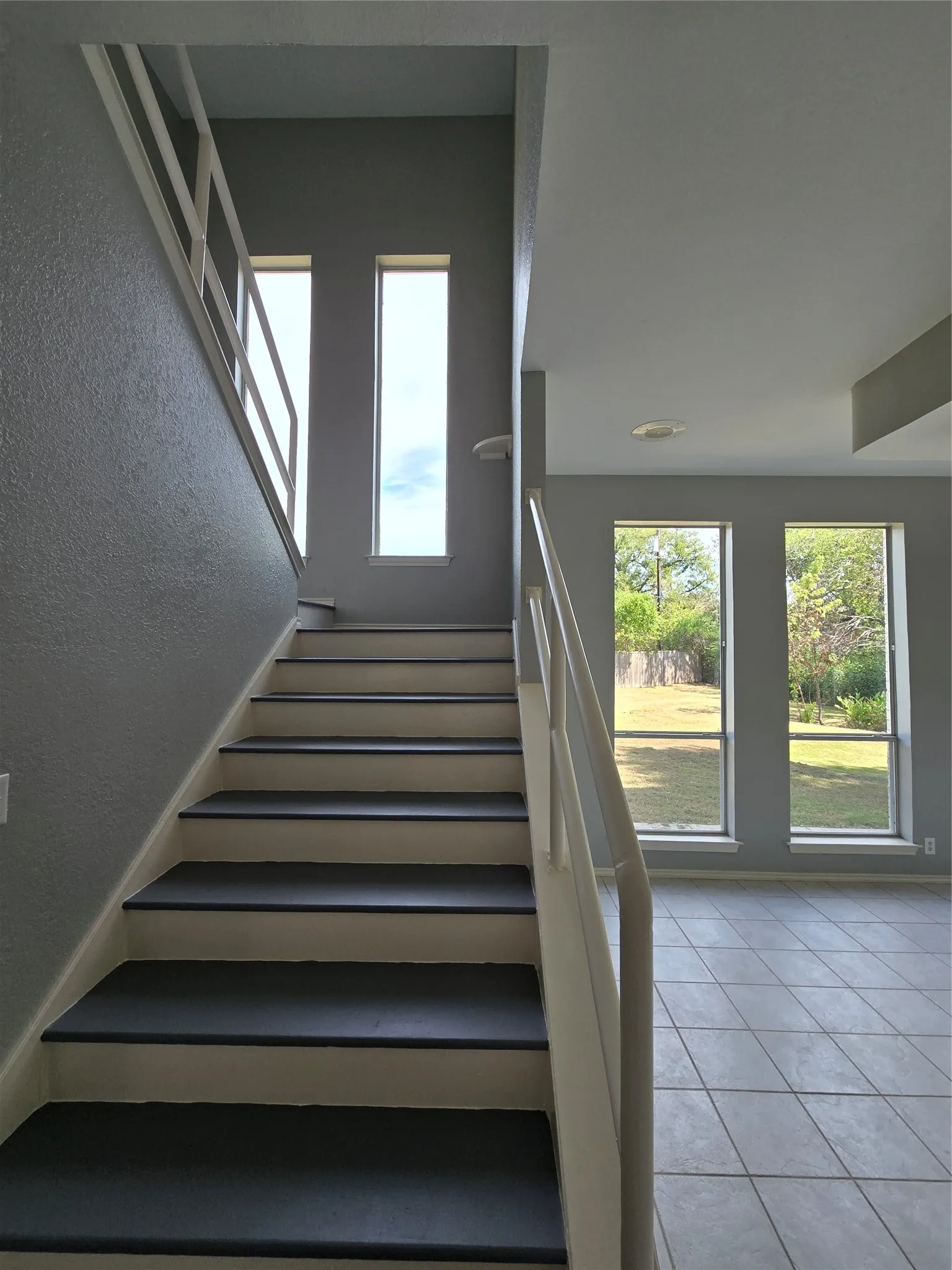 Staircase with painted risers and dark treads, complemented by multiple vertical windows