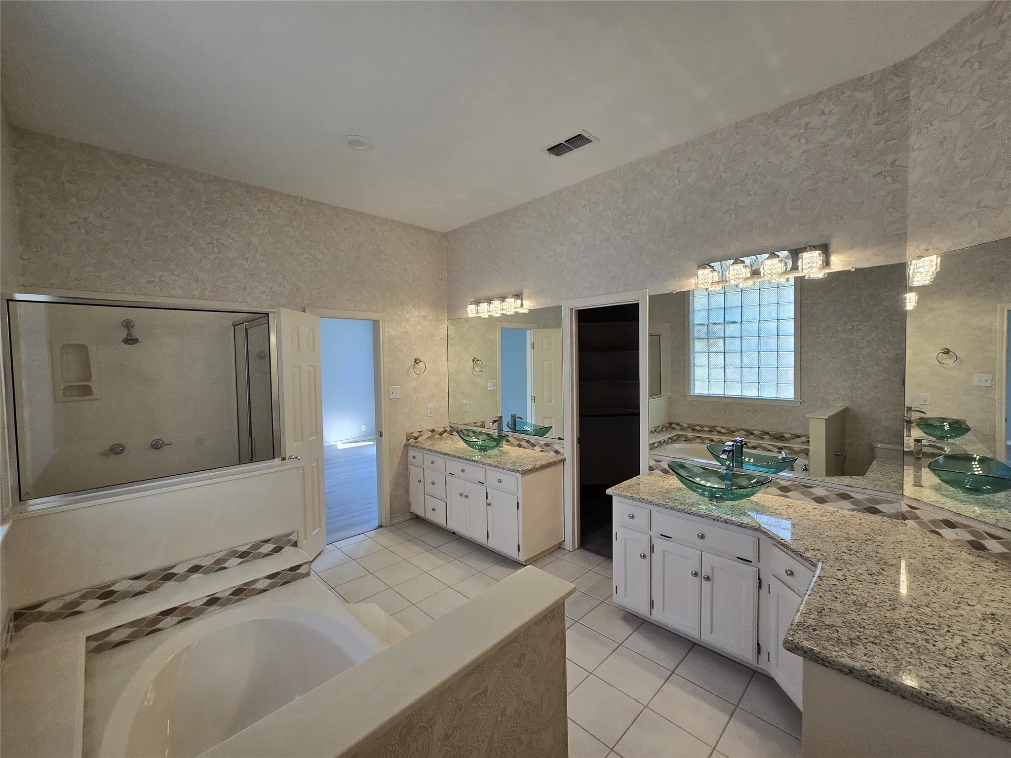 Dual vanity with vessel sinks, granite countertops, built-in soaking tub, and a separate glass-enclosed shower