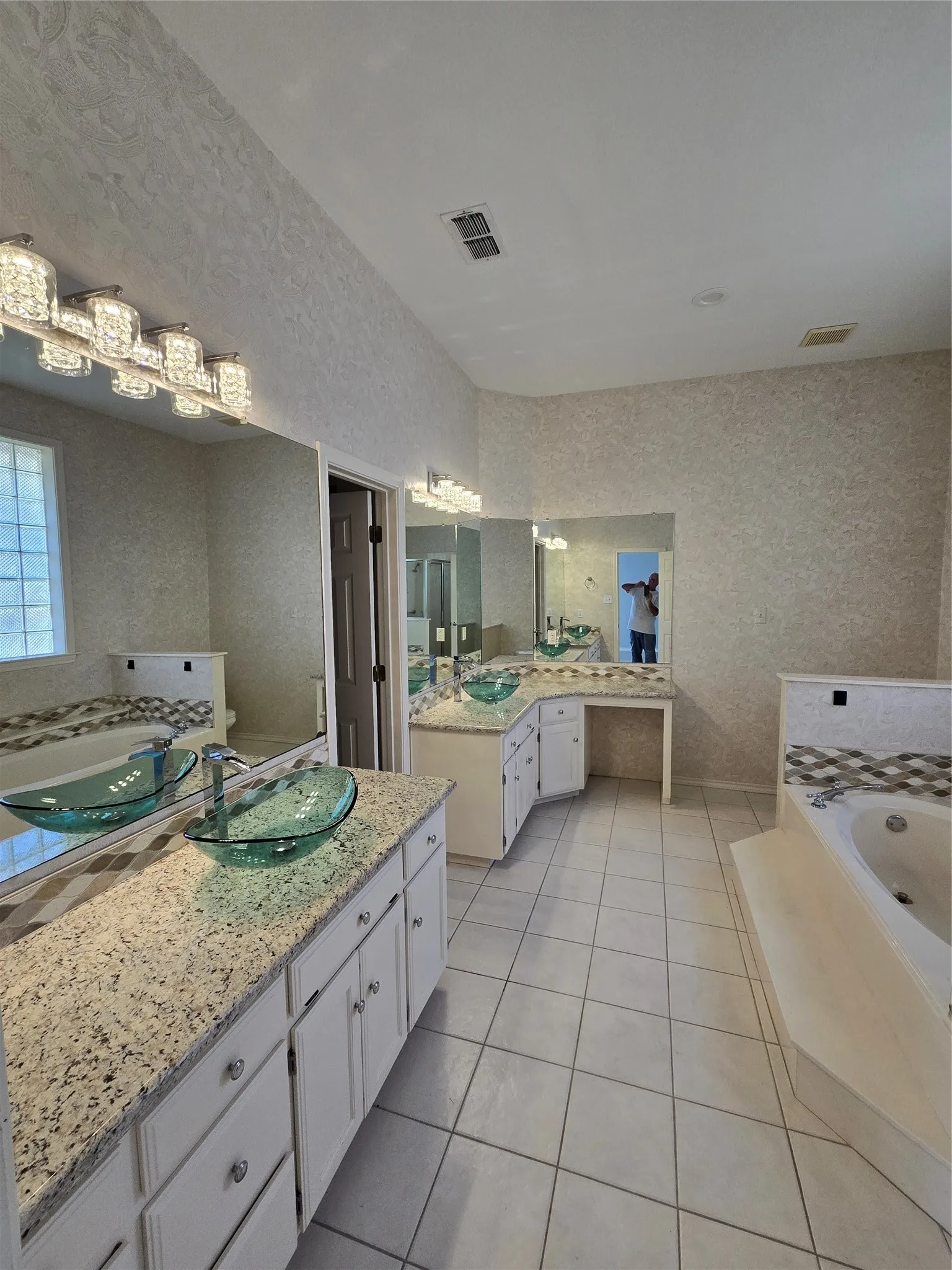 Dual vanity with granite countertops, integrated vessel sinks, tiled flooring, and a built-in tub