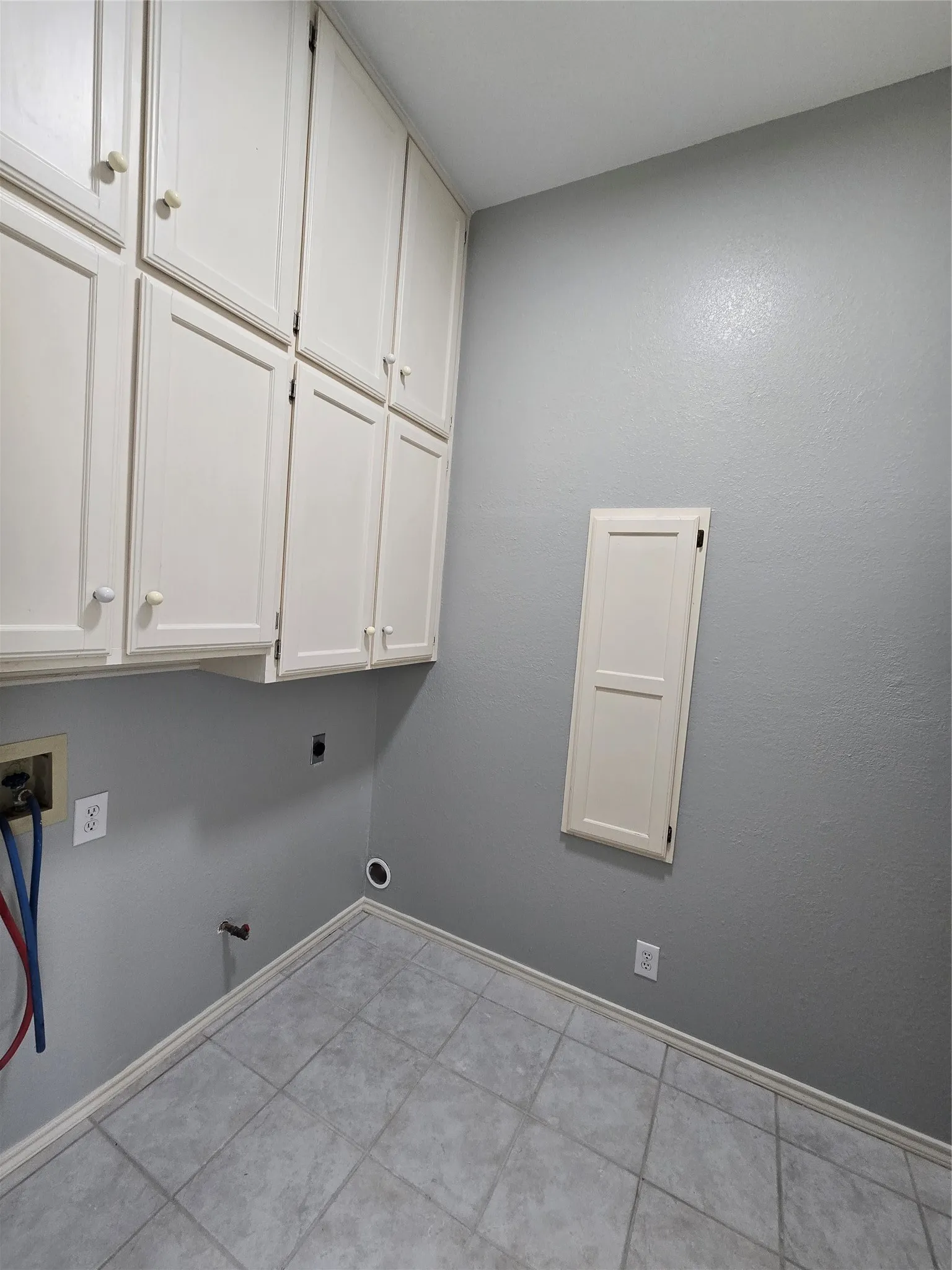 Upper cabinetry with panel doors, tiled flooring, and light gray wall paint