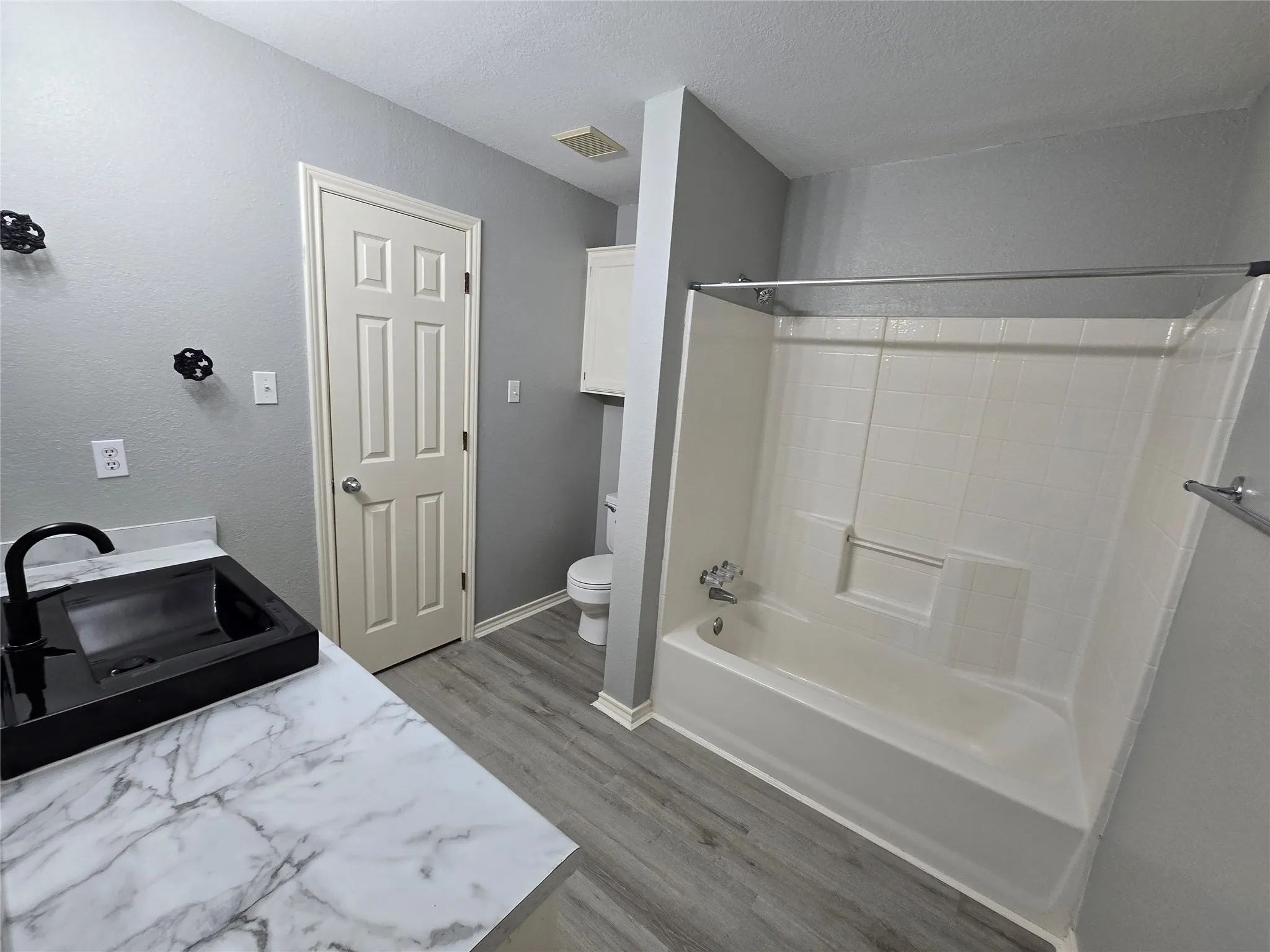 White marble-finish countertop with a black vessel sink and matte black faucet