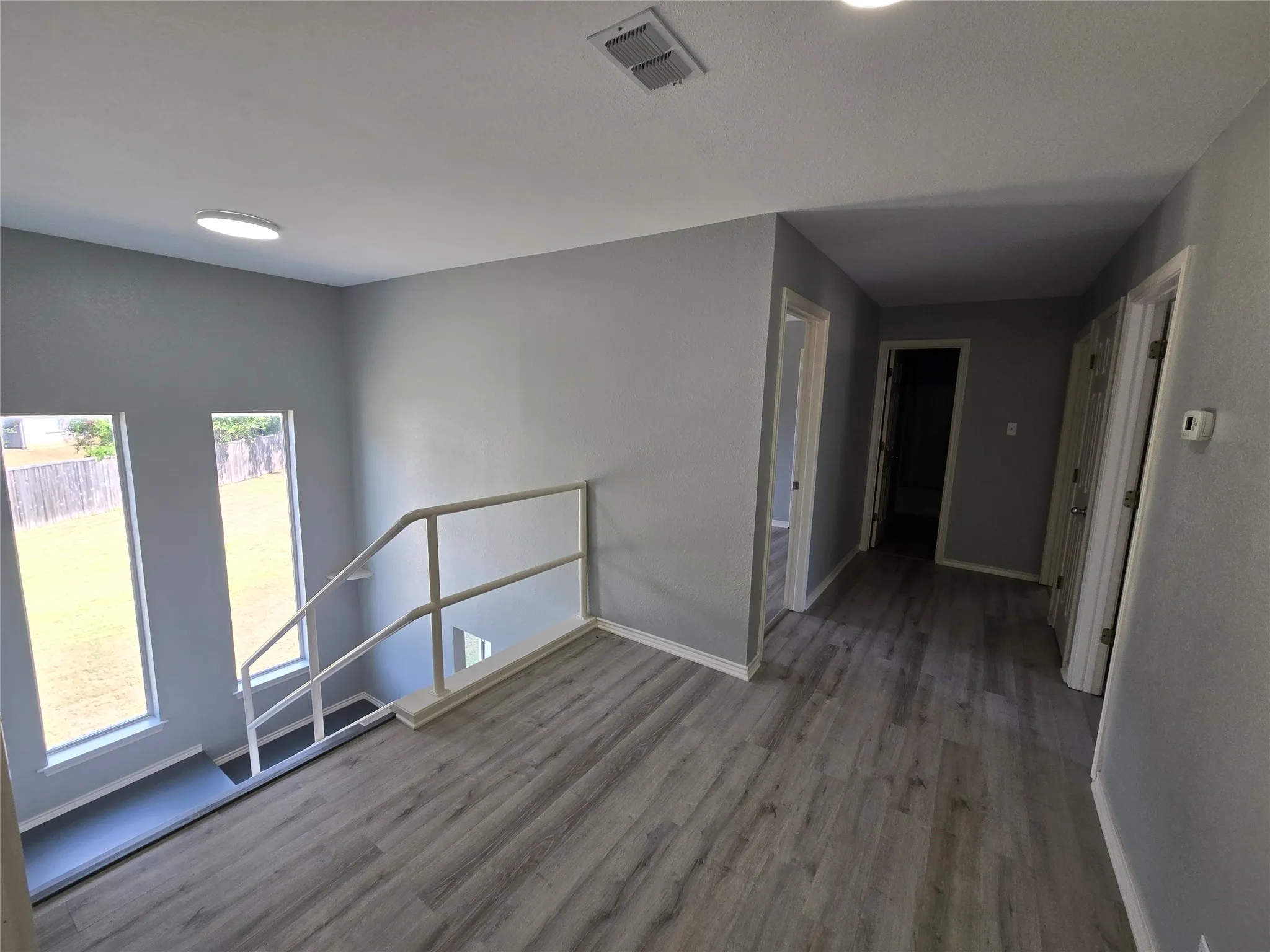 Open landing area featuring wood-finish flooring, recessed lighting, and a white railing