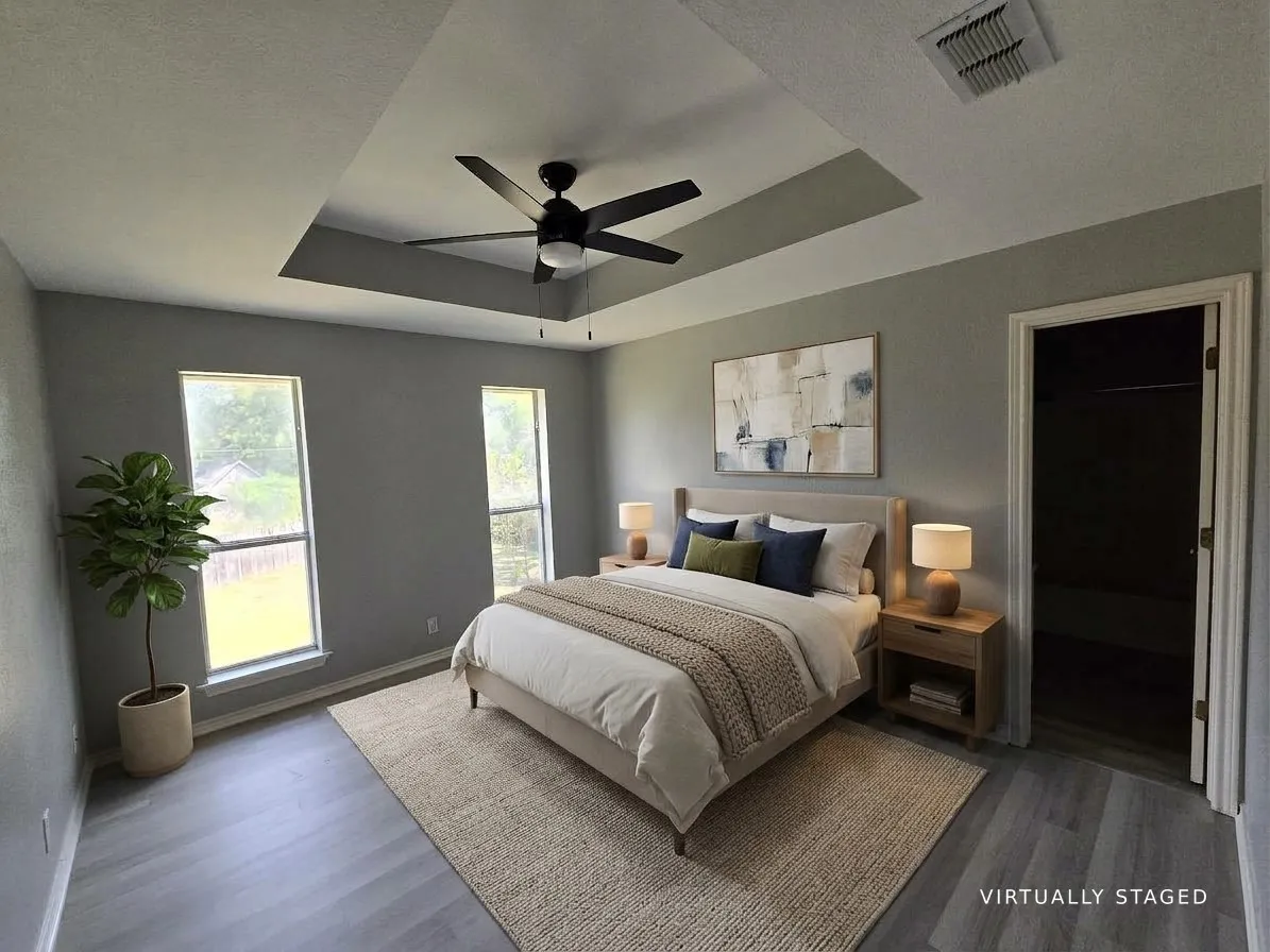 Tray ceiling with a ceiling fan, two windows, and wood-finish flooring