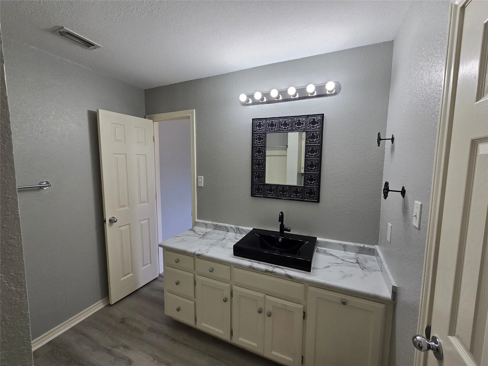 Single vanity with a vessel sink, white cabinetry, and a marbled countertop