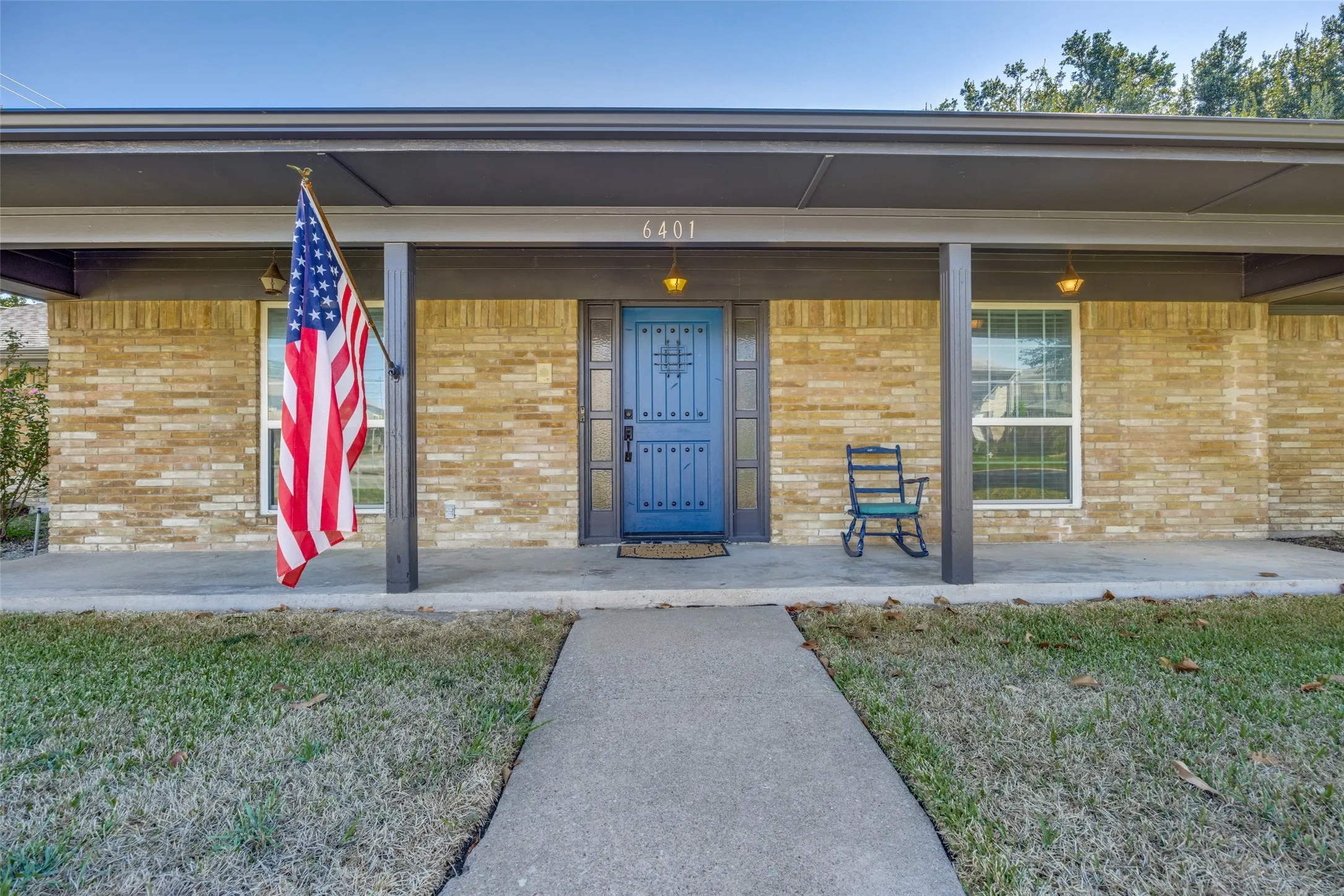 Brick exterior with a covered porch, blue entry door, and a concrete walkway