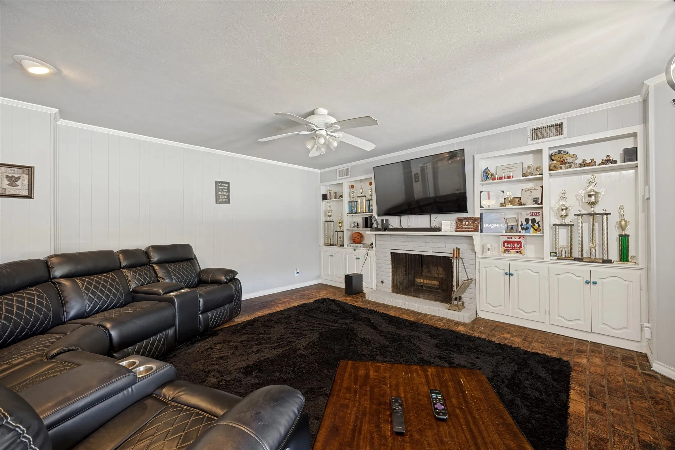Living room featuring a white brick fireplace, built-in shelving, wood-finish flooring, a ceiling fan, and recessed lighting