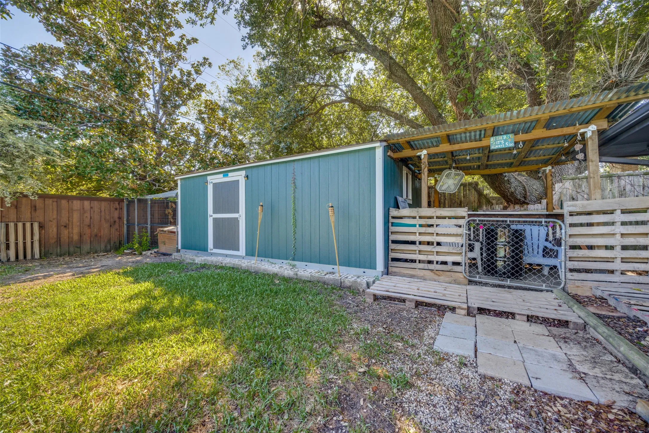 Backyard featuring a shed with a covered patio area, wood fencing, and mature trees