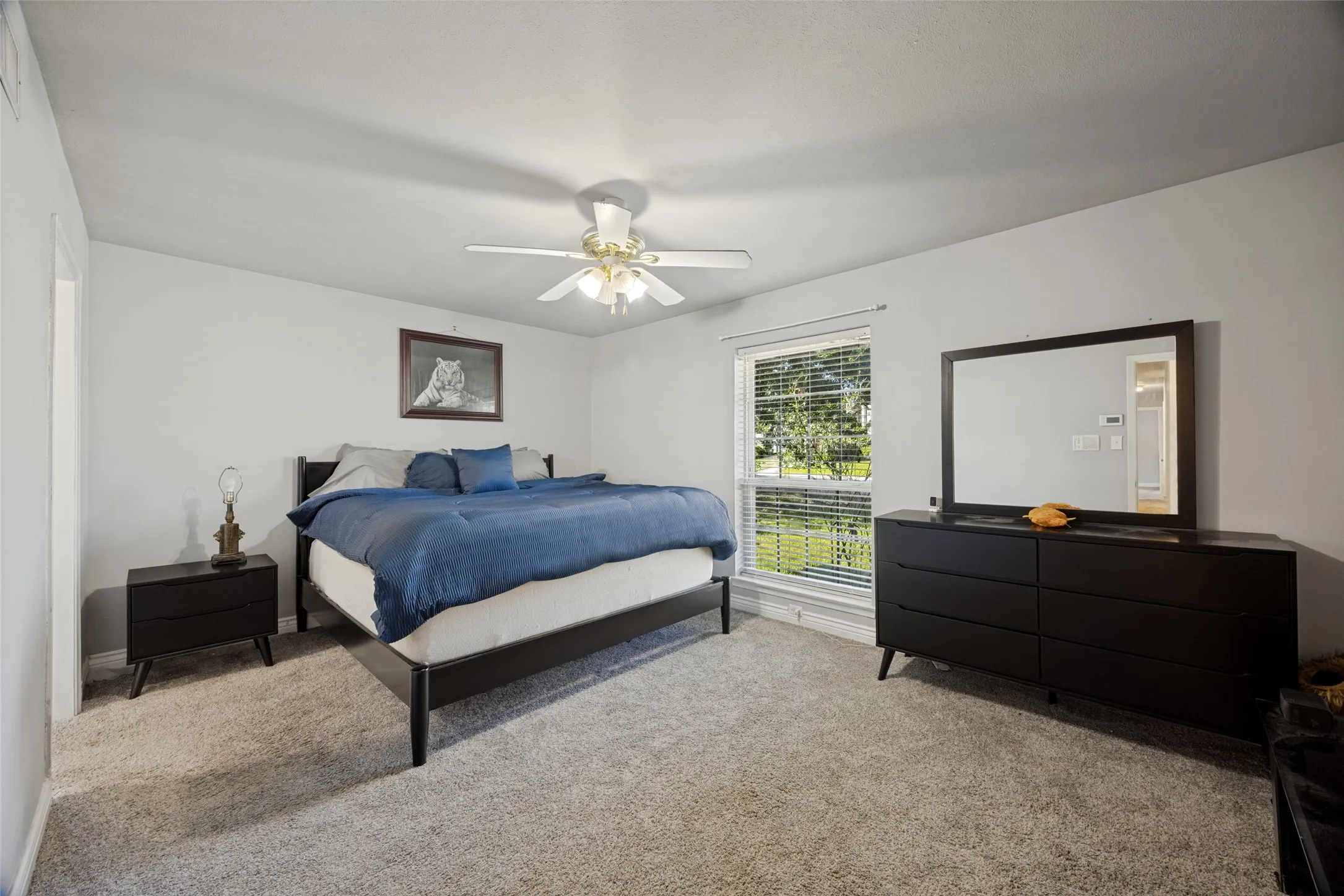 Plush carpet flooring, a window with blinds, and a ceiling fan with integrated lighting