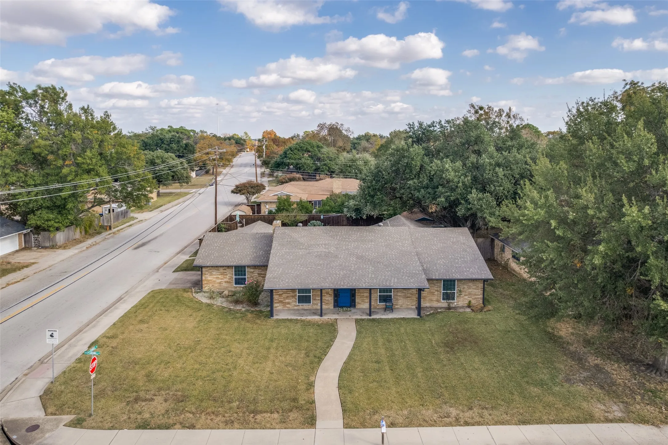 Single-story stone exterior home with a covered front porch, a blue front door, and a paved walkway