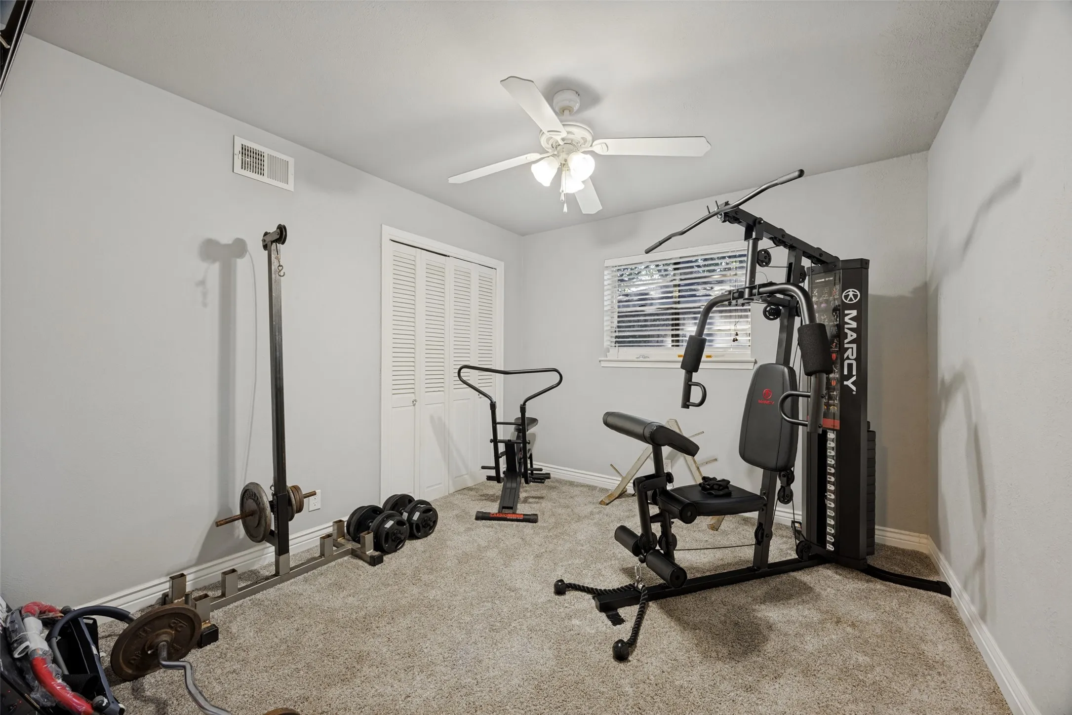 Carpeted room featuring a ceiling fan, a window with blinds, and bi-fold closet doors