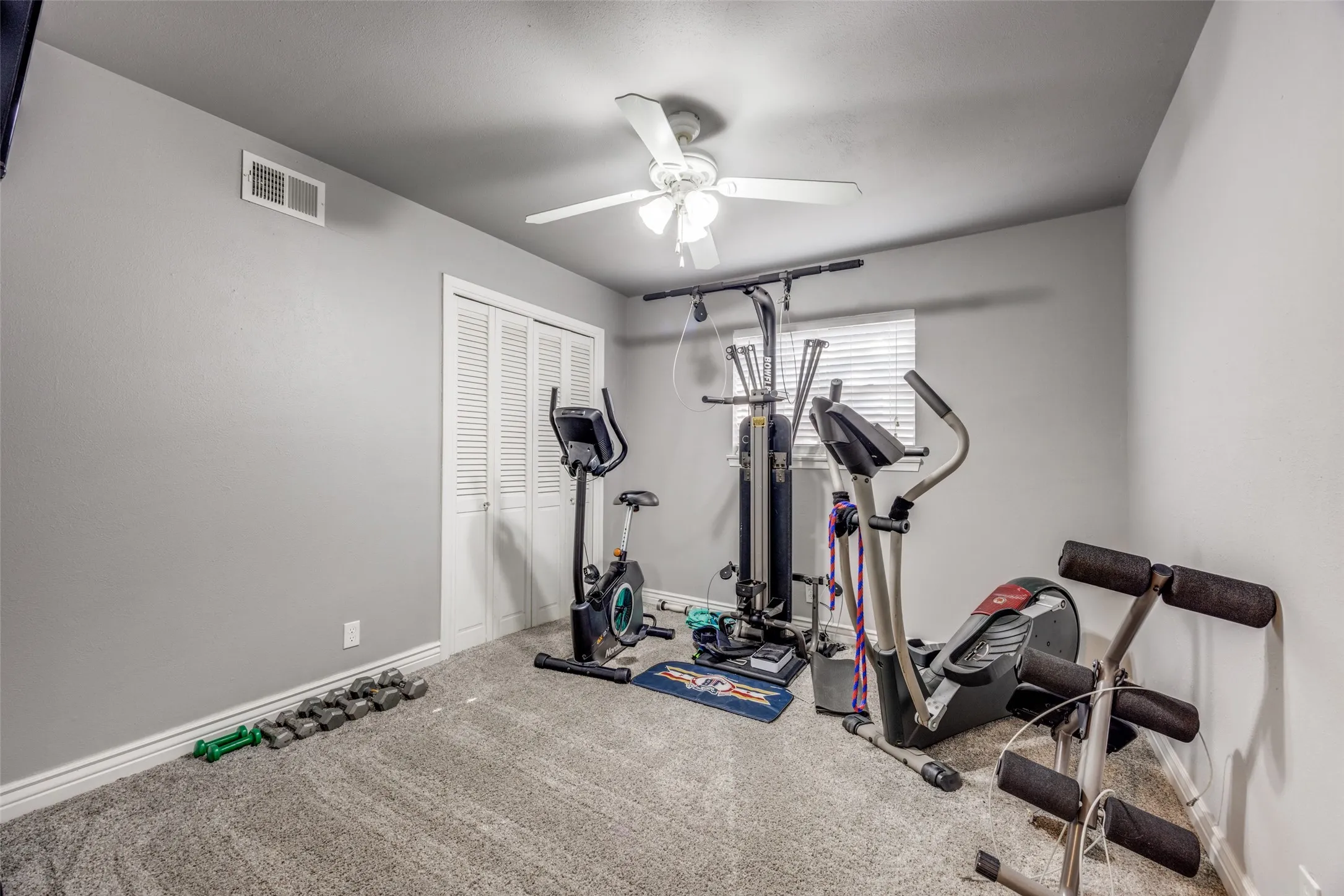 Carpeted room featuring a ceiling fan, window with blinds, and bi-fold closet doors