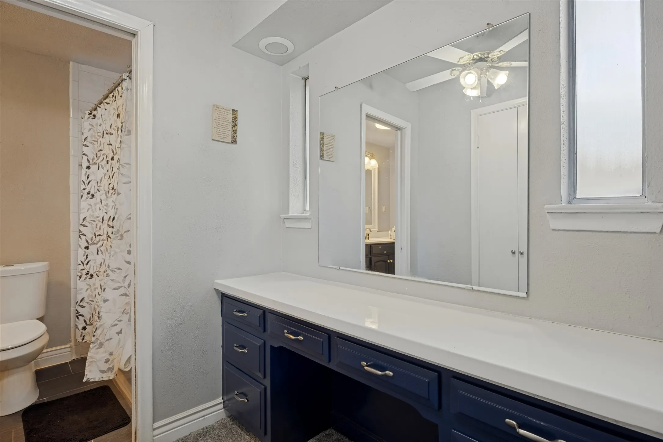 Extended vanity with multiple drawers, white countertop, and expansive wall mirror