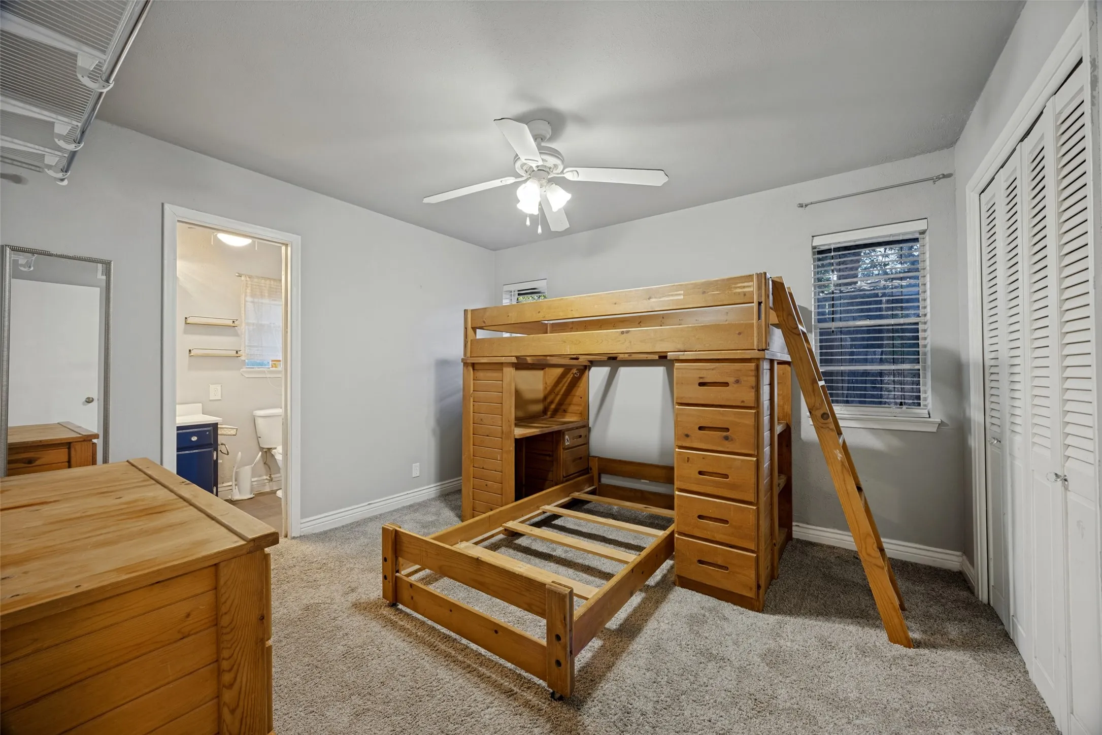 Carpeted flooring, ceiling fan, window with blinds, and louvered bi-fold closet doors