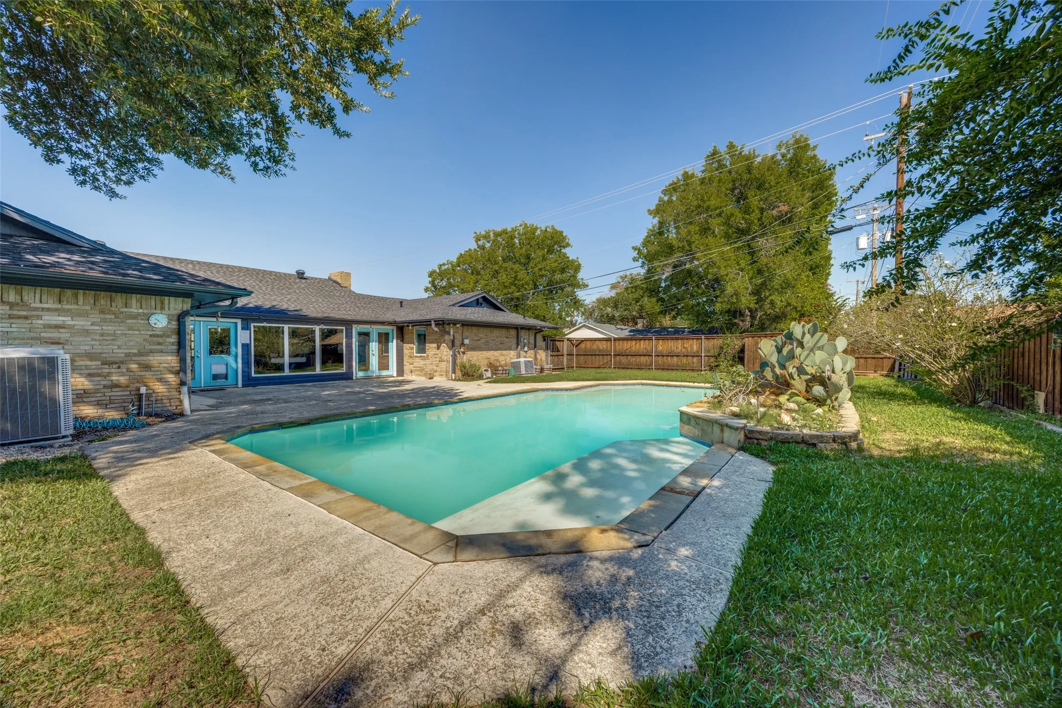 In-ground swimming pool with a concrete surround, stone planter, and fenced perimeter