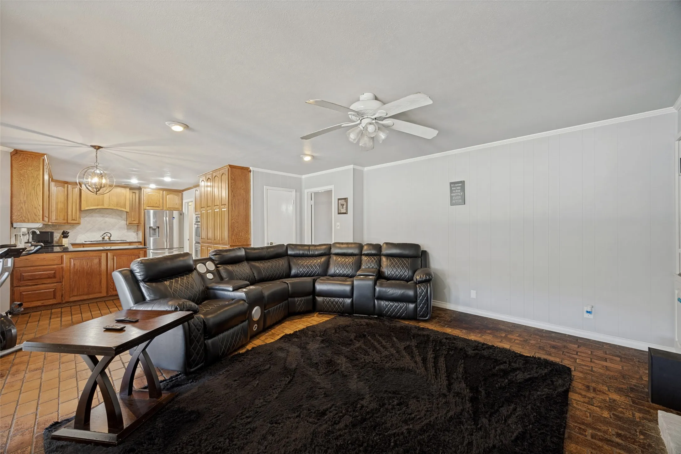 Open-concept living space featuring wood-finish flooring, a ceiling fan with integrated lighting, recessed lighting, and a kitchen with wood cabinetry and stainless steel appliances