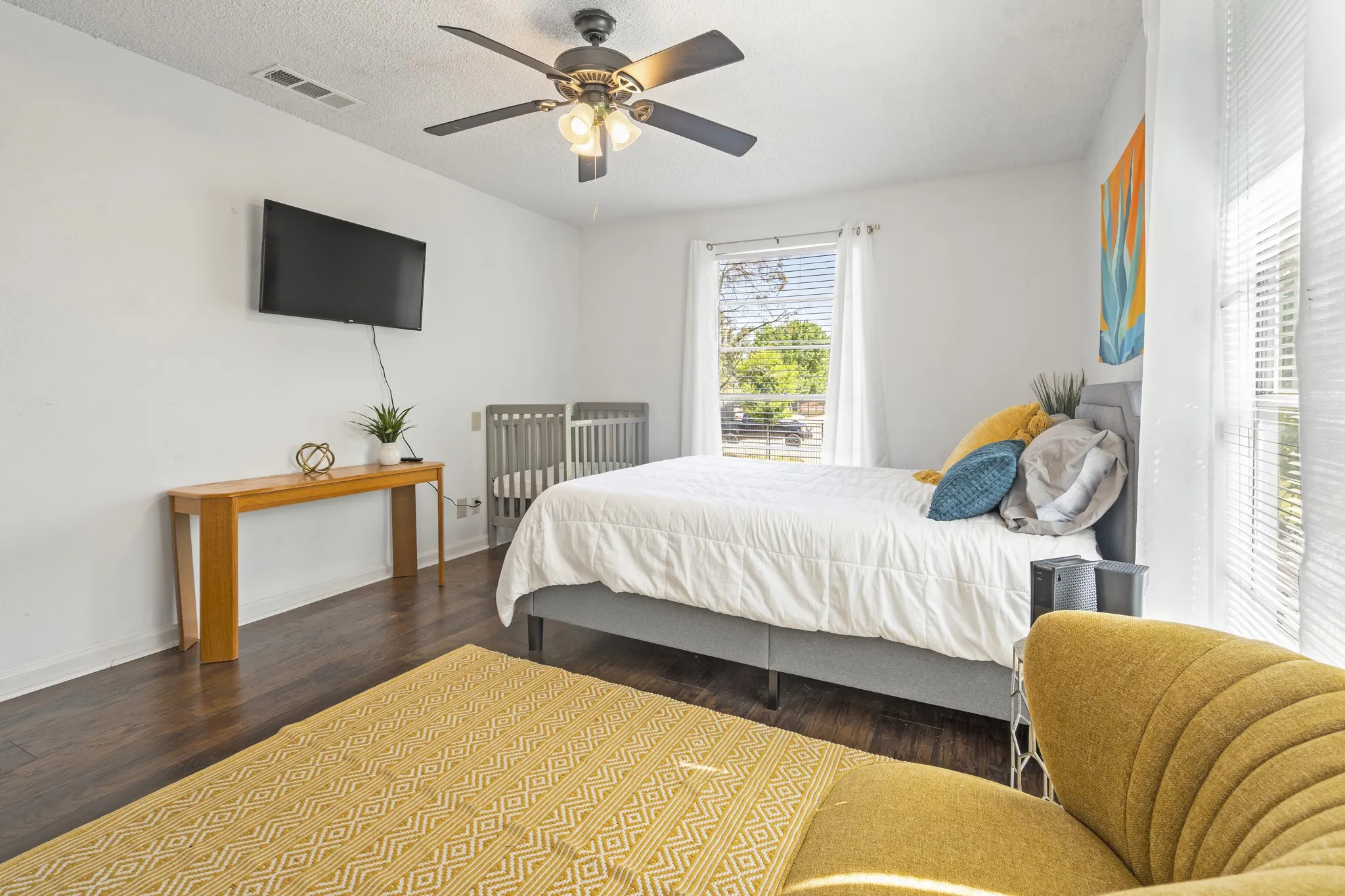 Wood-finish flooring, ceiling fan with integrated lighting, window with blinds, and white interior walls