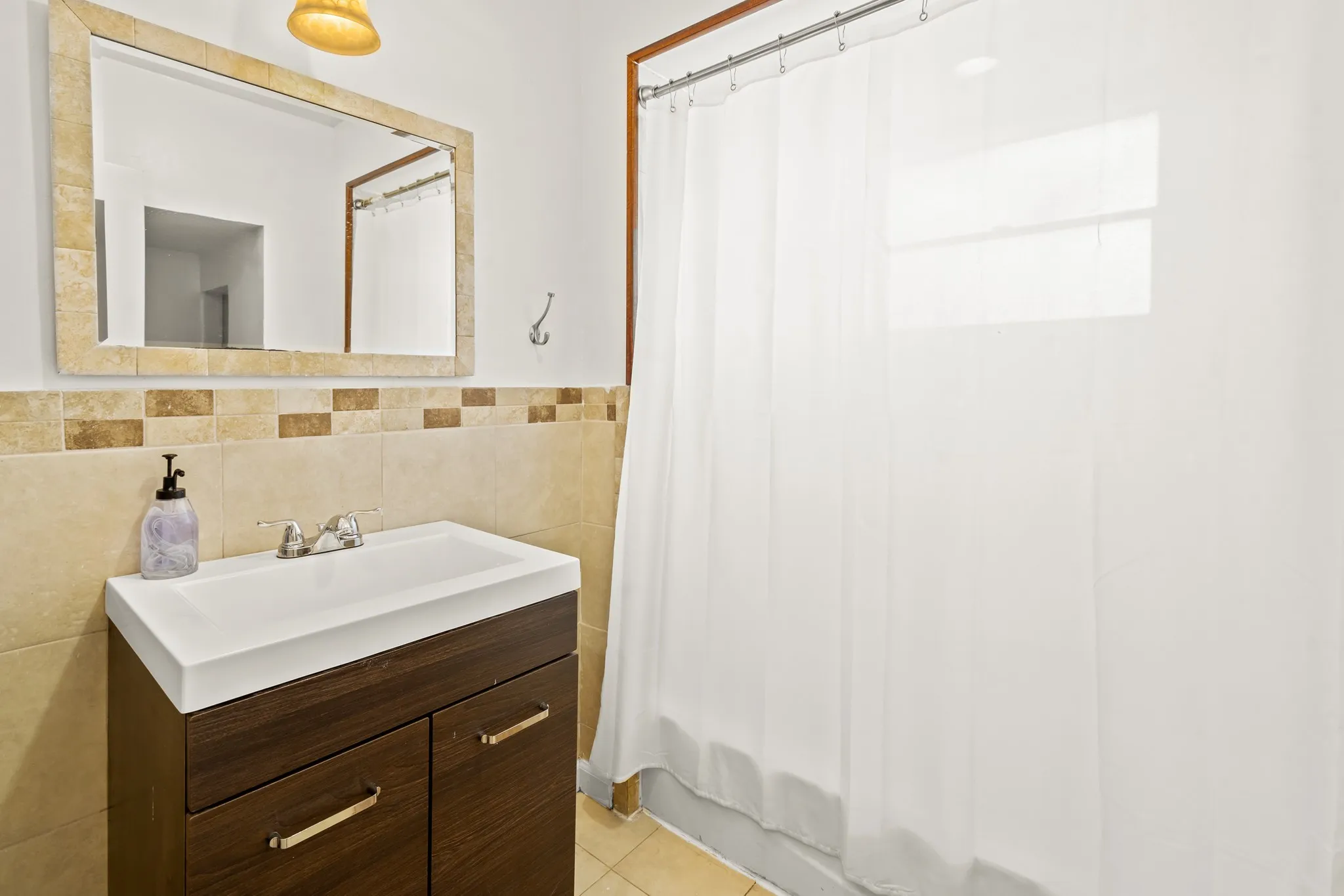 Wood-finish vanity with integrated sink, chrome faucet, and bronze-tone hardware