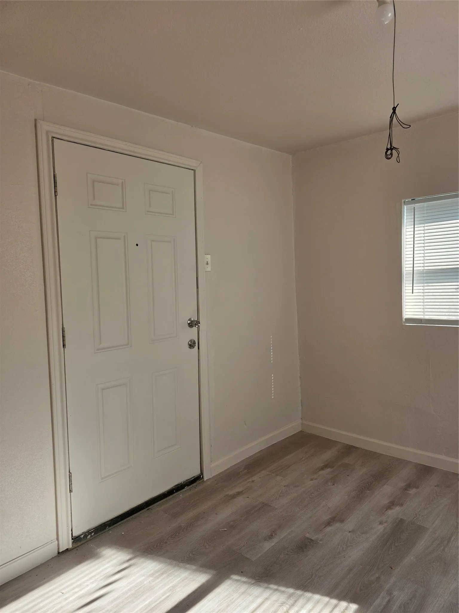 Wood-finish flooring with white baseboards and neutral wall paint