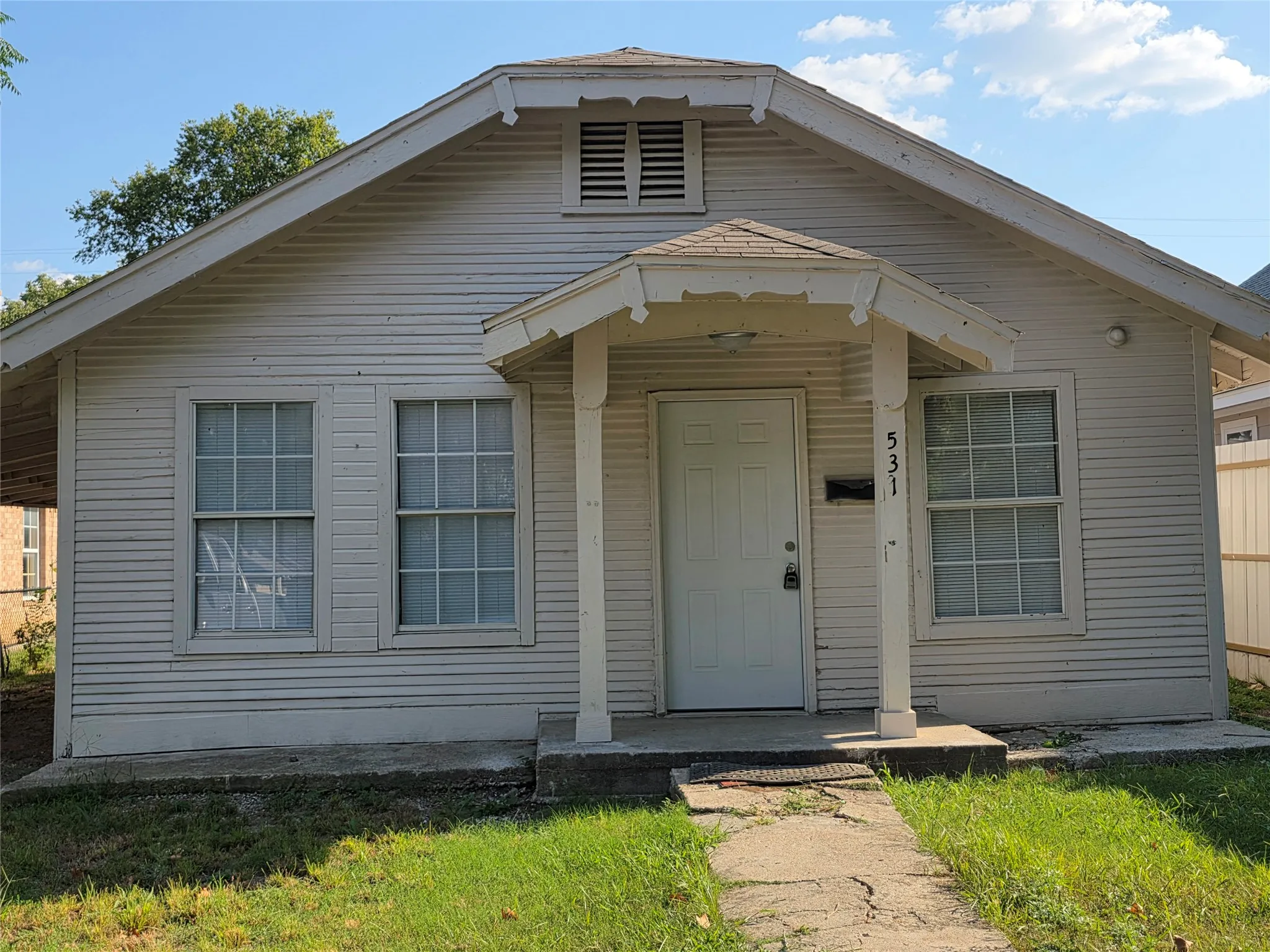 Charming cottage-style home featuring horizontal siding exterior, a covered front porch with decorative brackets, and a gabled roofline