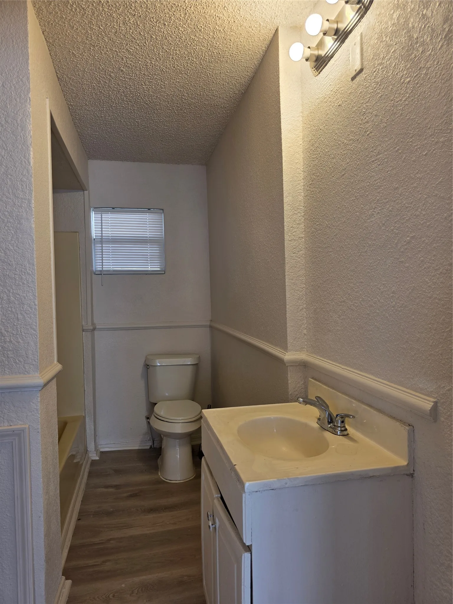 Bathroom featuring wood-finish flooring, a vanity with an integrated sink, and wainscoting