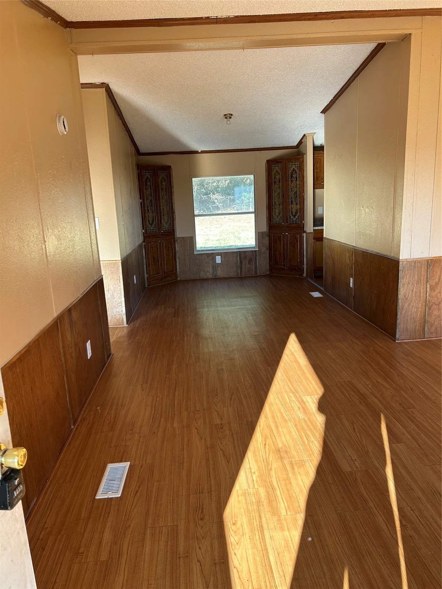 Wood-finish flooring, half-wall wood paneling, built-in cabinetry, and a window