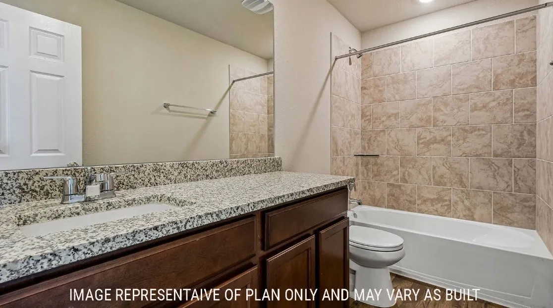 Granite-style countertop with integrated sink, dark wood-finish vanity cabinetry, and tiled shower surround with a built-in tub