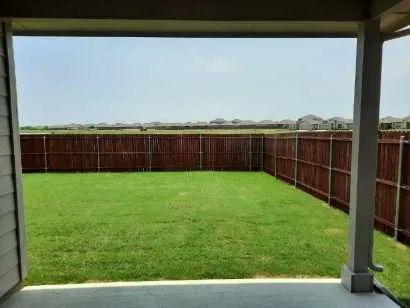 Covered patio leading to a private backyard with a wood fence and green lawn