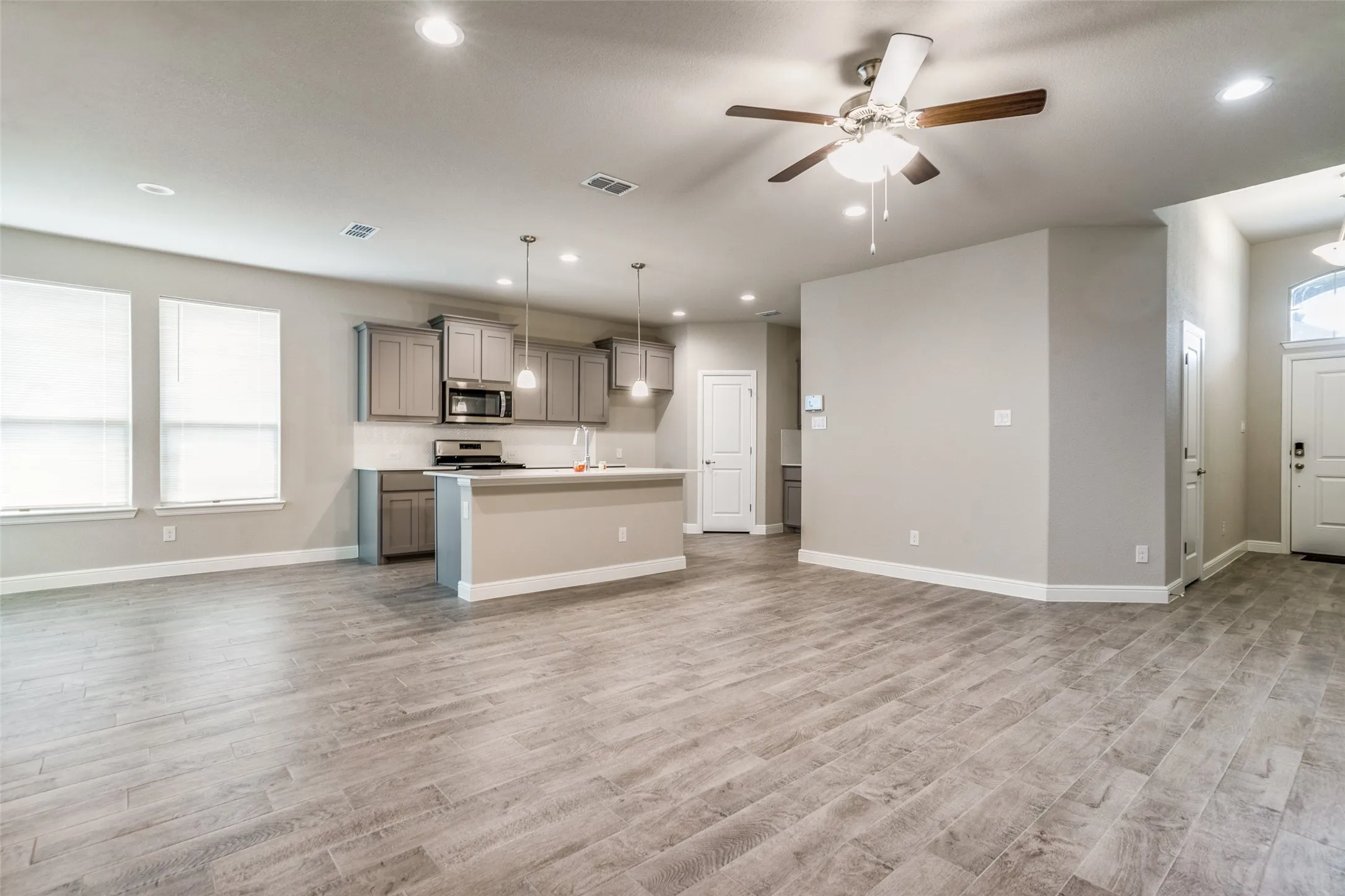 Open-concept living area with wood-finish flooring, recessed lighting, and a ceiling fan