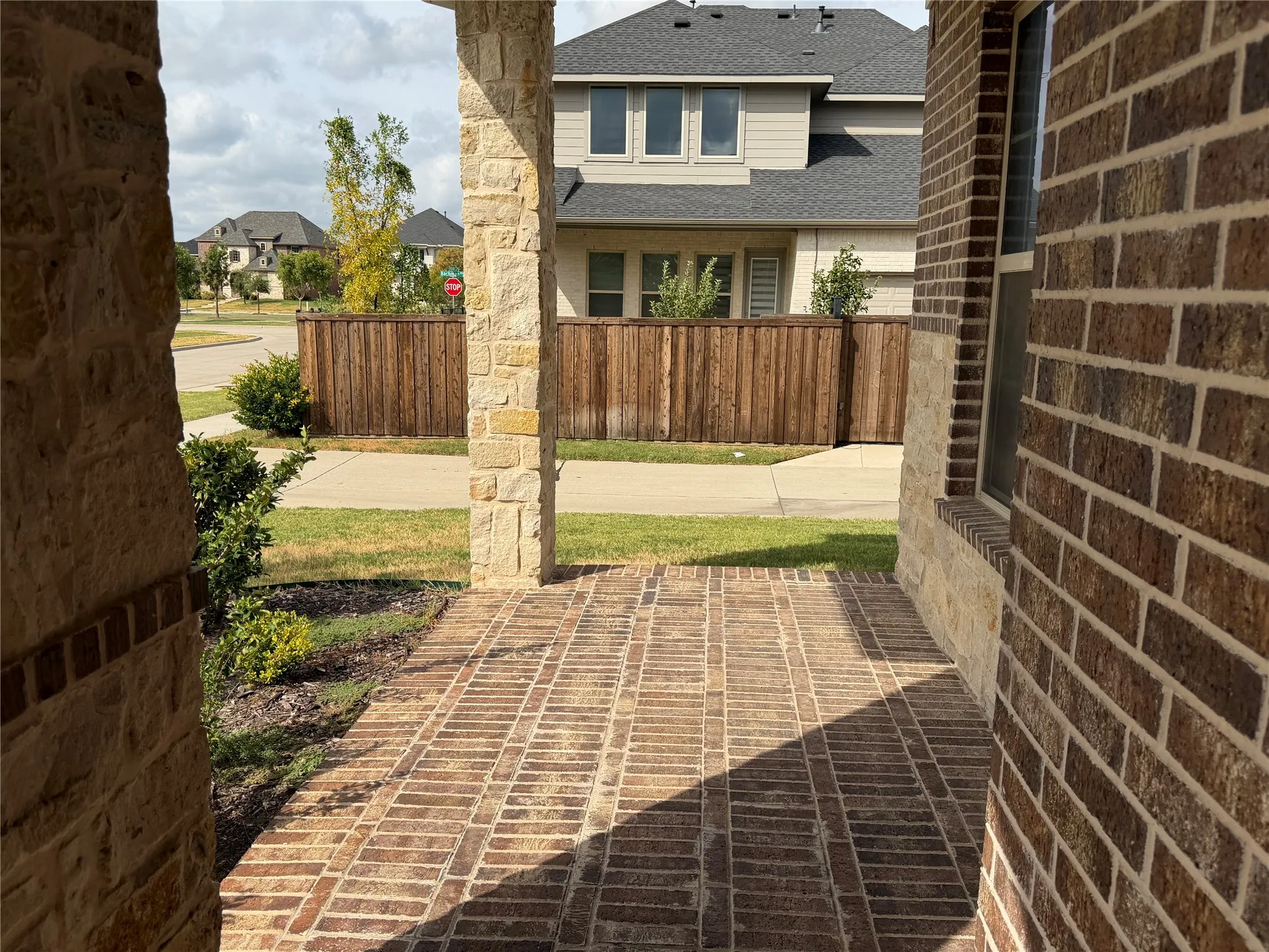 Brick and stone exterior with a covered front porch featuring a brick-patterned floor