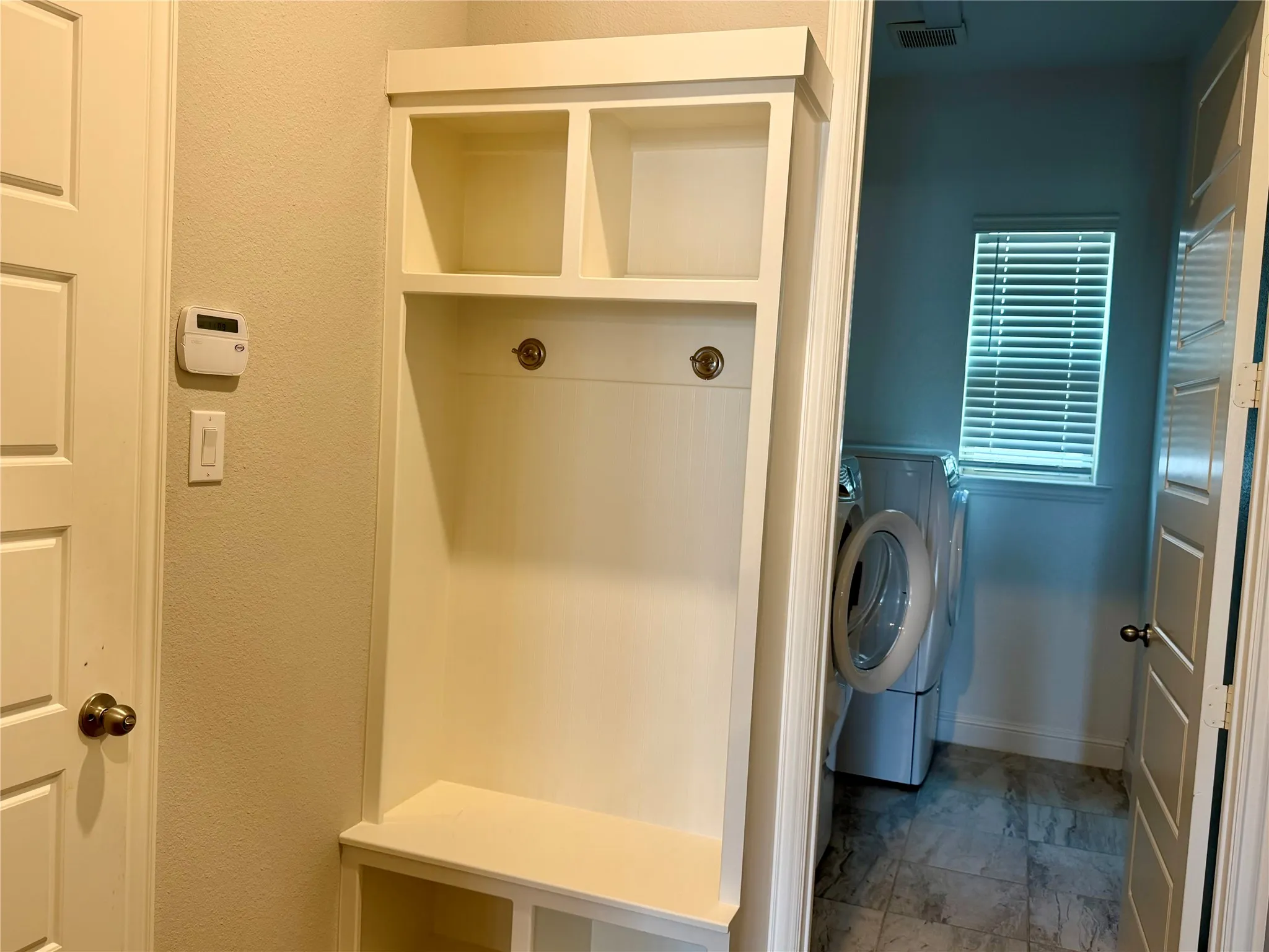 Built-in white storage unit with cubbies and coat hooks