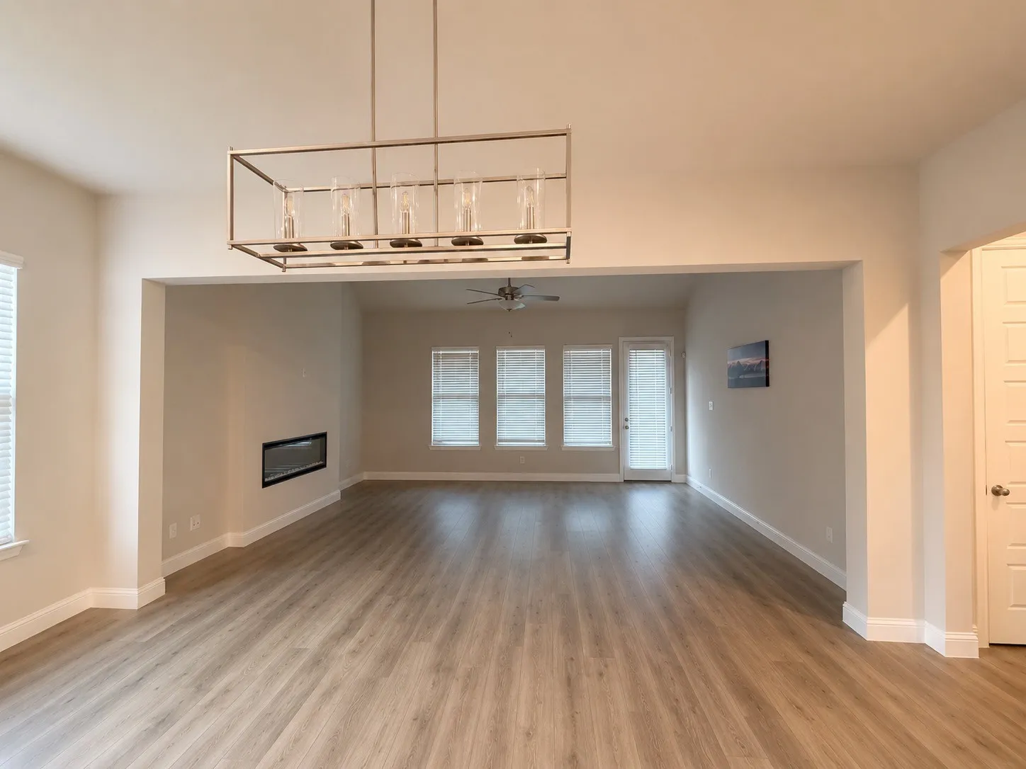Texas sized family room with expansive interior, wood-finish flooring, a built-in linear fireplace, and an overhead chandelier