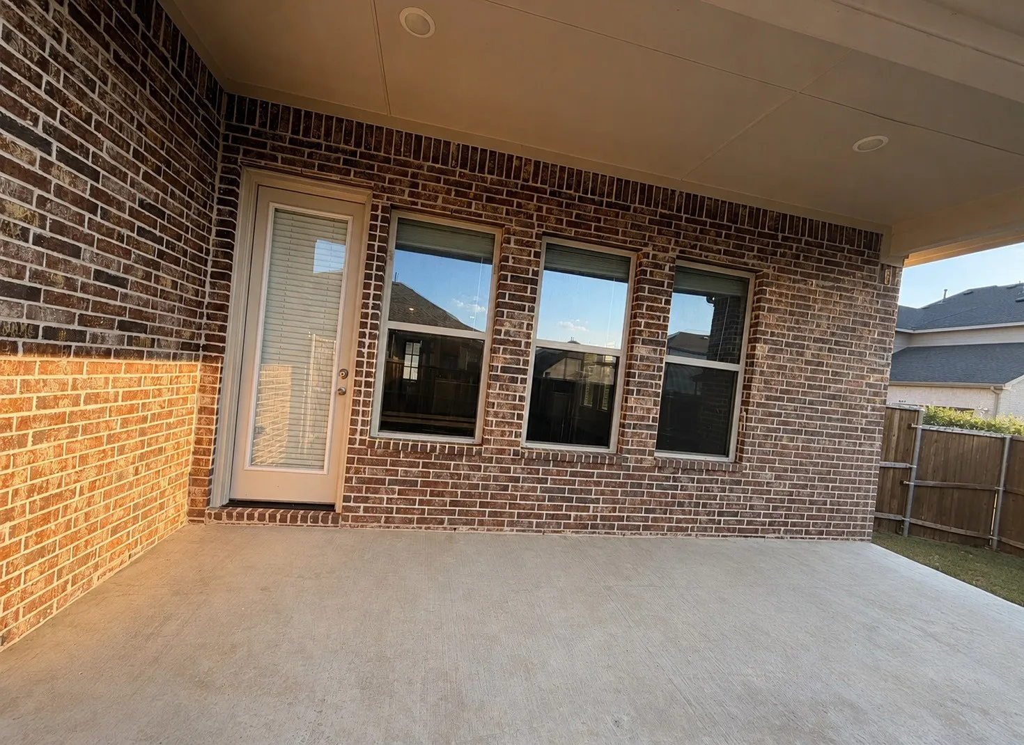 Covered patio with brick exterior, concrete flooring, and recessed lighting