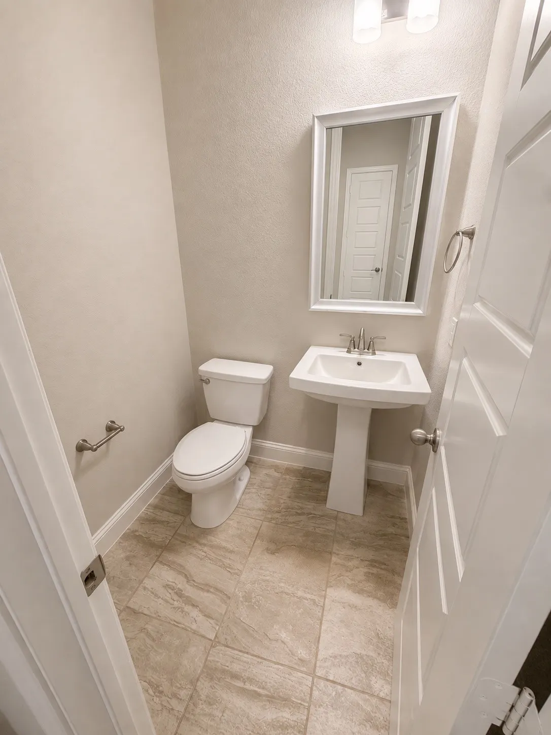 Guest bath downstairs with pedestal sink with a framed mirror and wall-mounted lighting