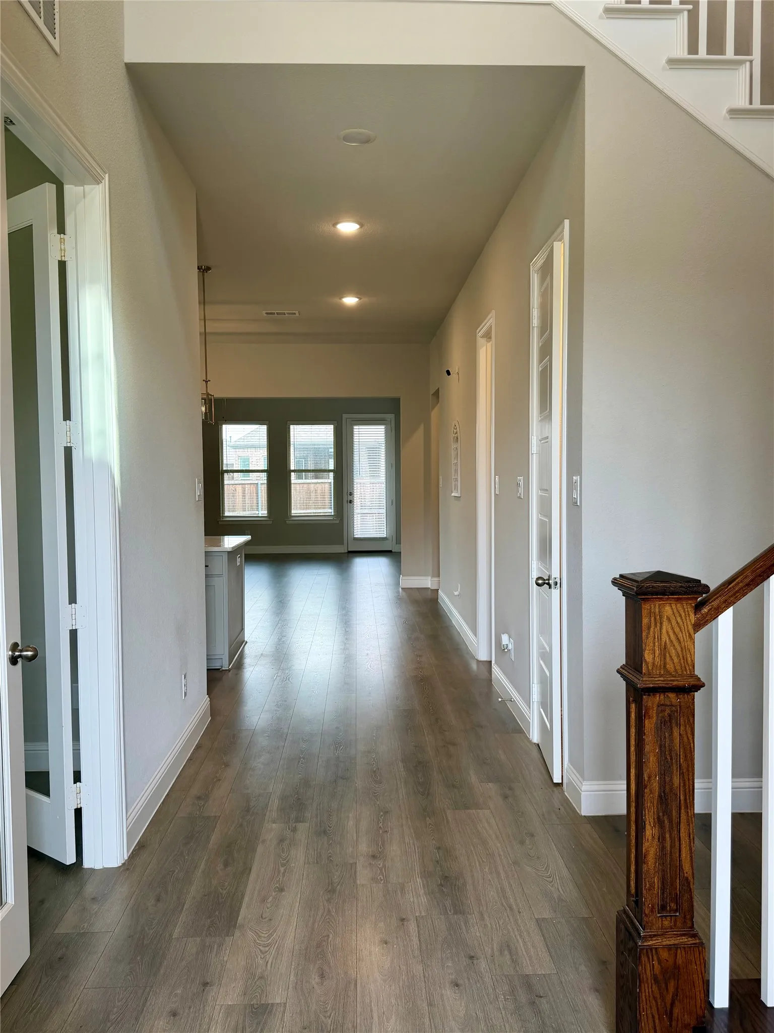 Wood-finish flooring throughout, recessed lighting, and a wood newel post with white balusters