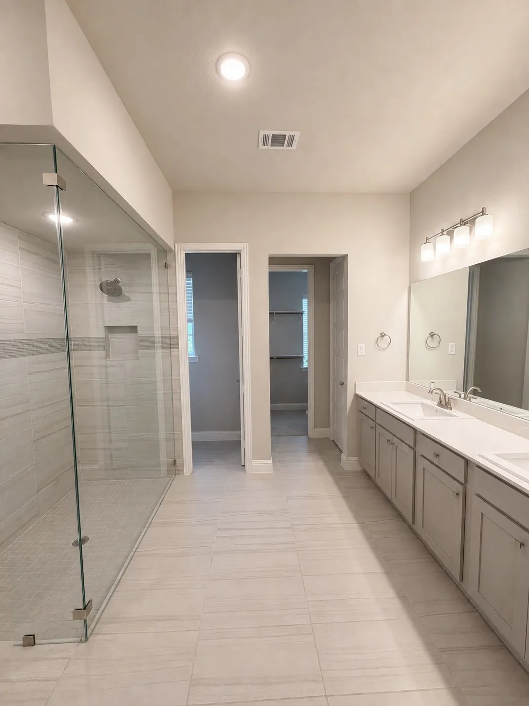 Walk-in shower with clear glass enclosure and tile surround