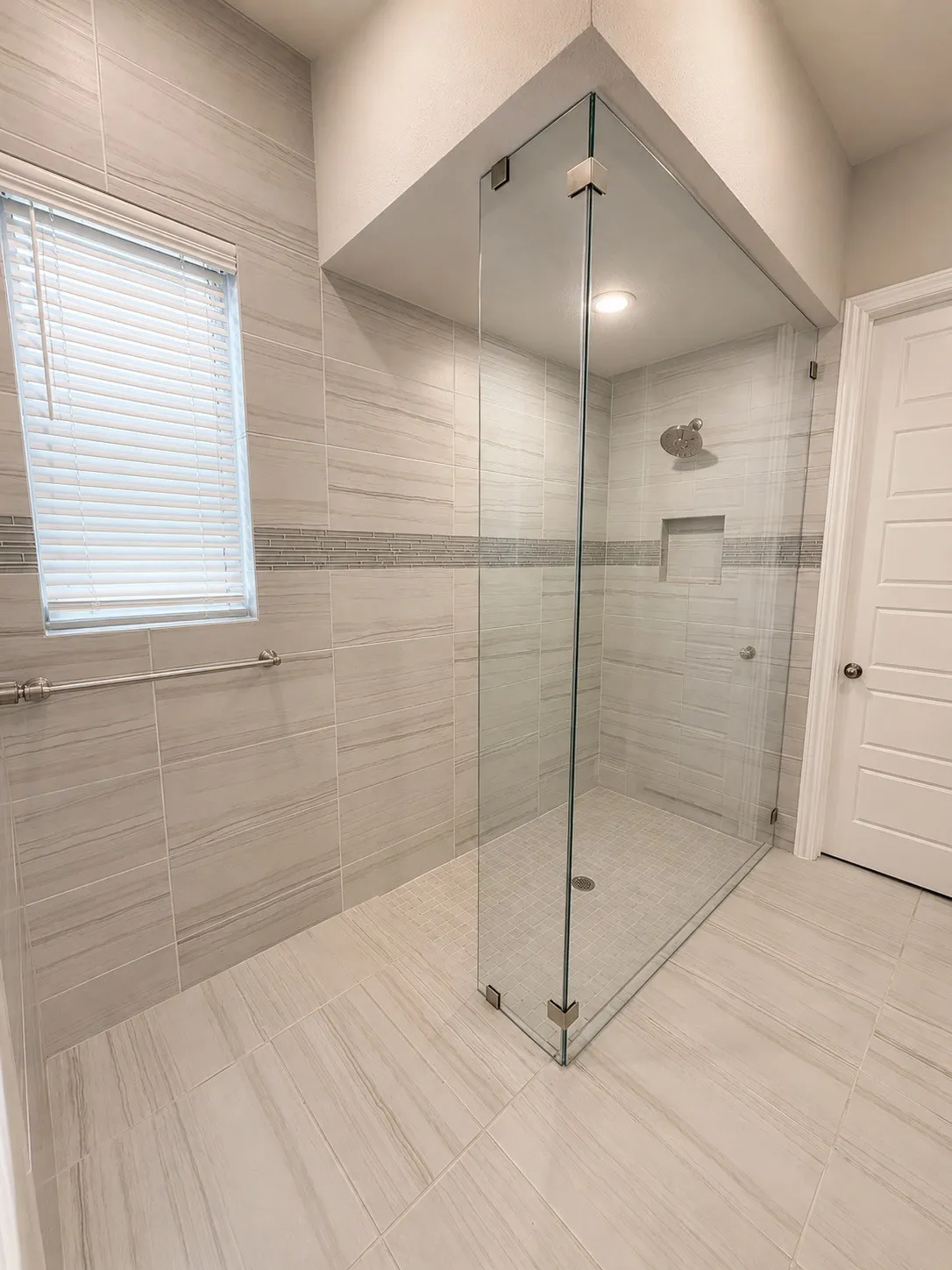 Walk-in shower with clear glass enclosure and recessed niche
