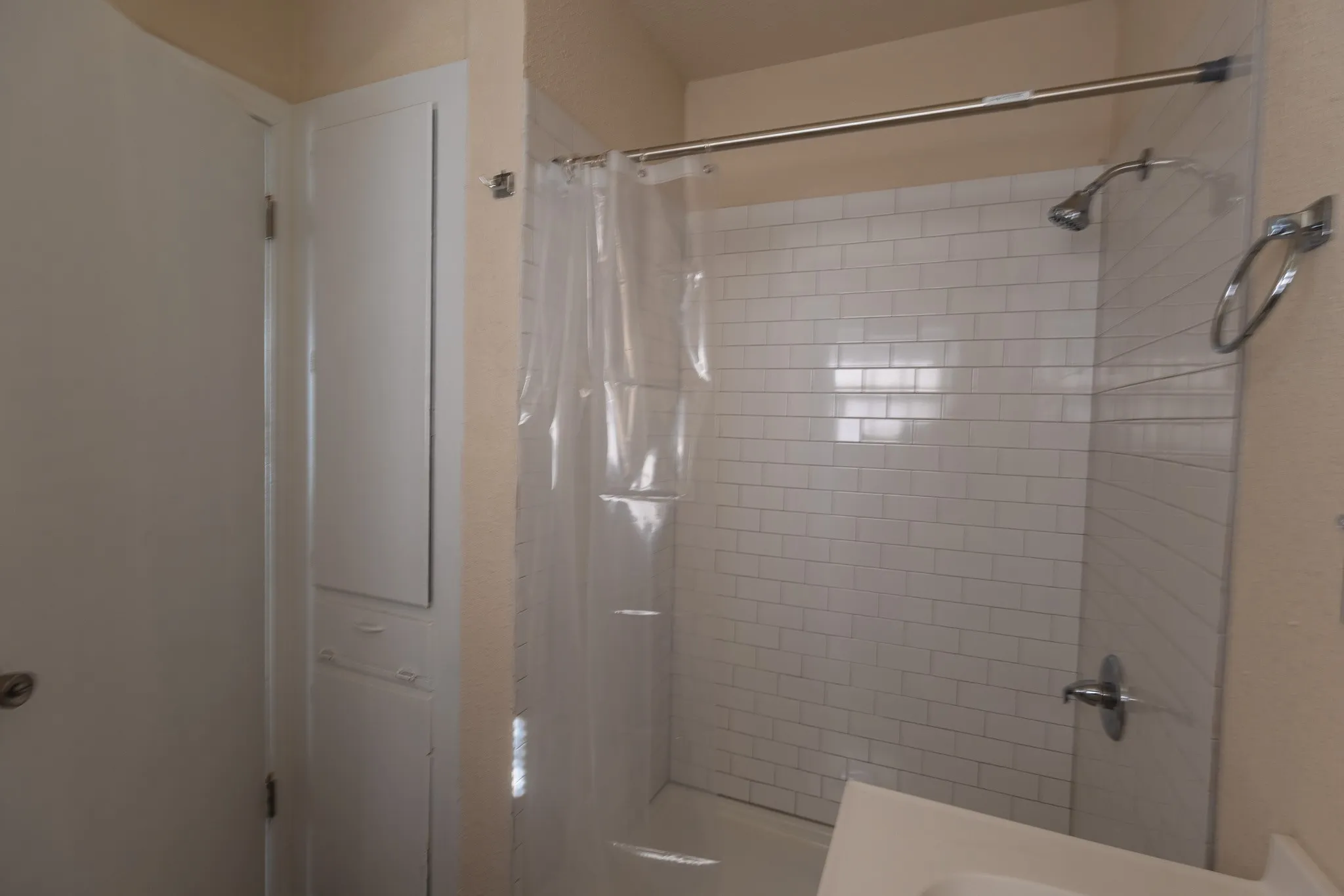 Shower enclosure with white subway tile, chrome fixtures, and built-in storage cabinetry