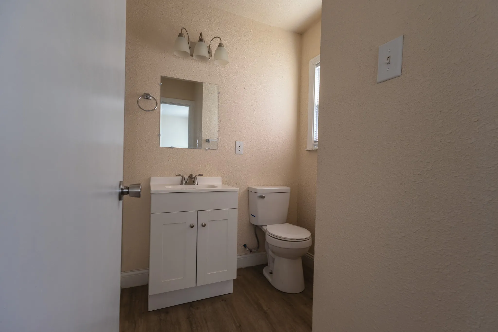 White vanity with cabinet storage, a white ceramic sink, and a chrome faucet
