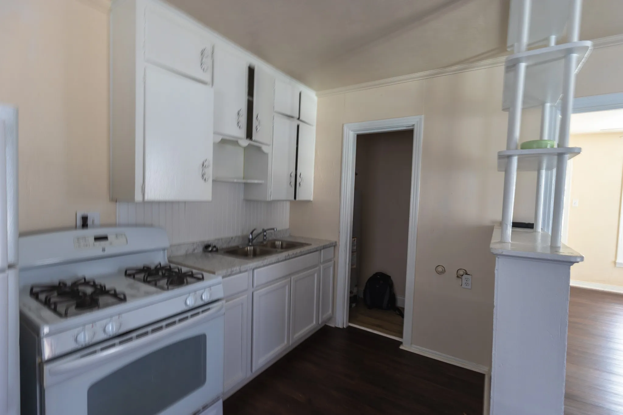 Kitchen featuring white cabinetry, light-toned countertops, white beadboard backsplash, and wood-finish flooring