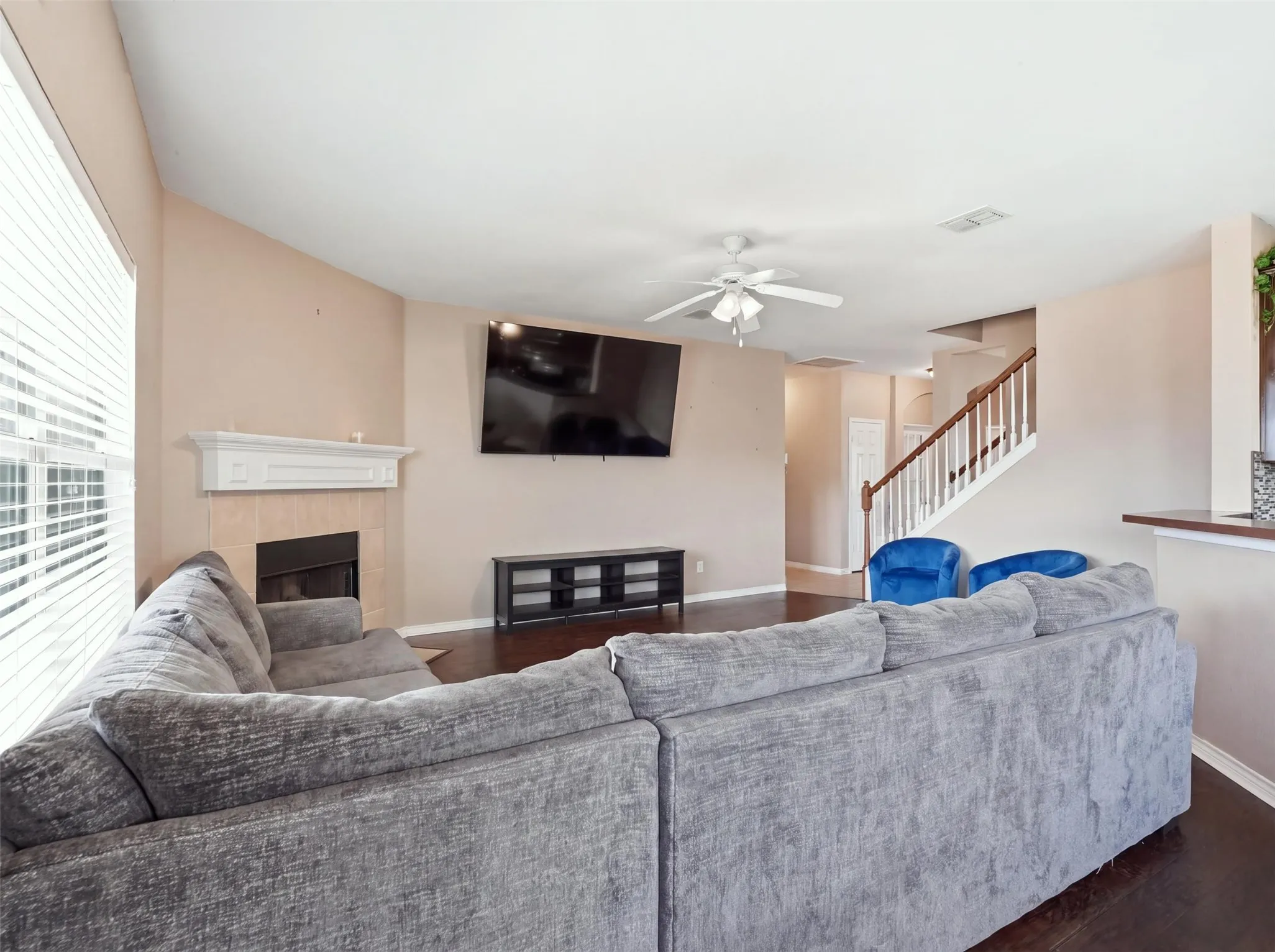 Living area featuring a fireplace with a mantel, wood-finish flooring, and a ceiling fan