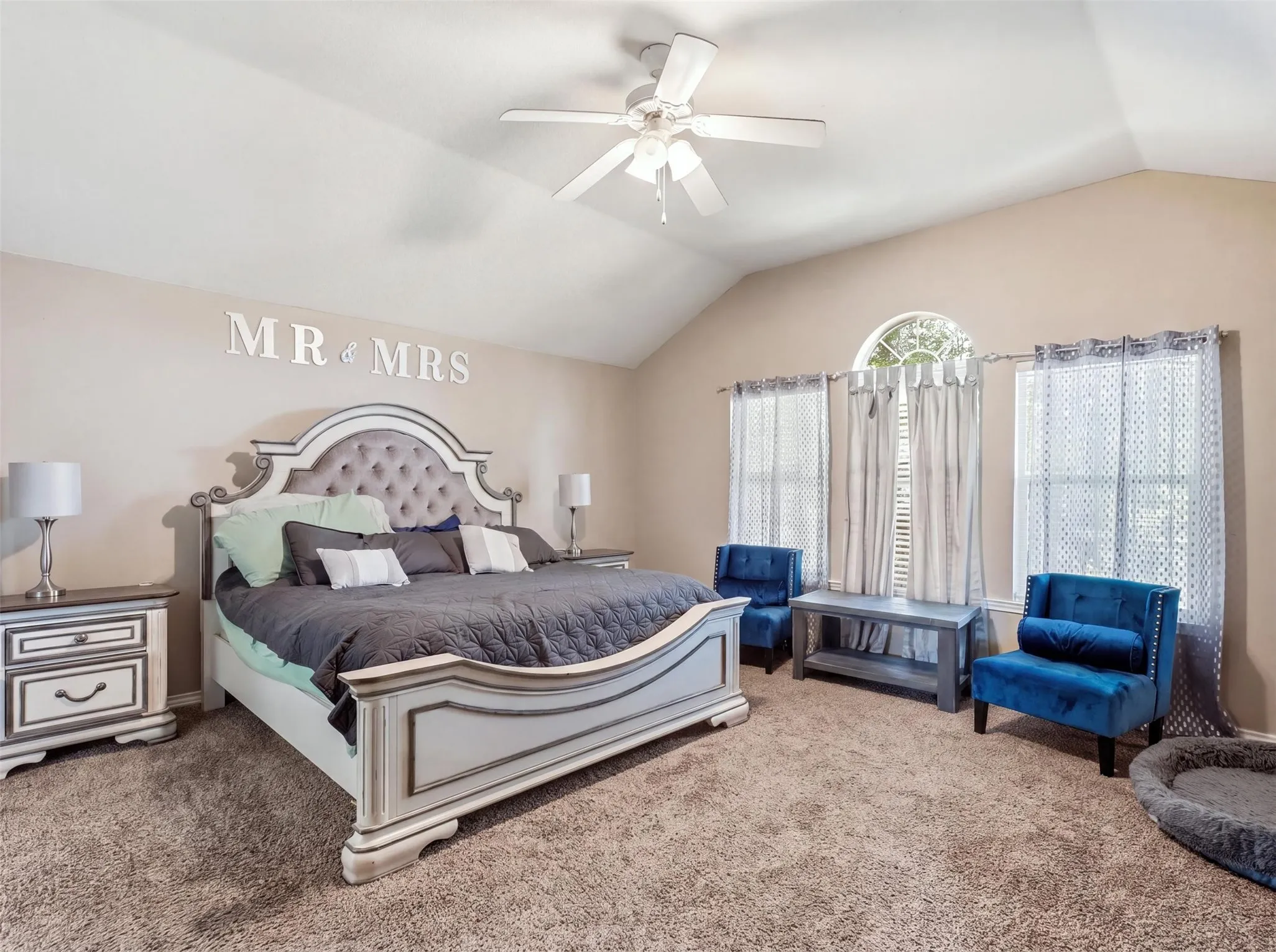 Vaulted ceiling, ceiling fan, arched transom window, two window openings, and wall-to-wall carpeting