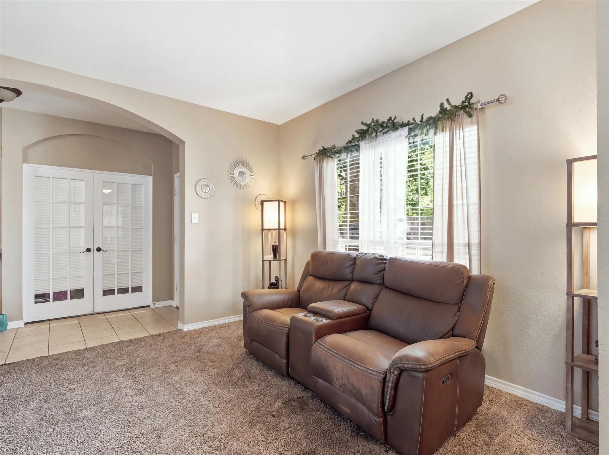 Archway entry with double French doors, large window with blinds, and carpeted flooring