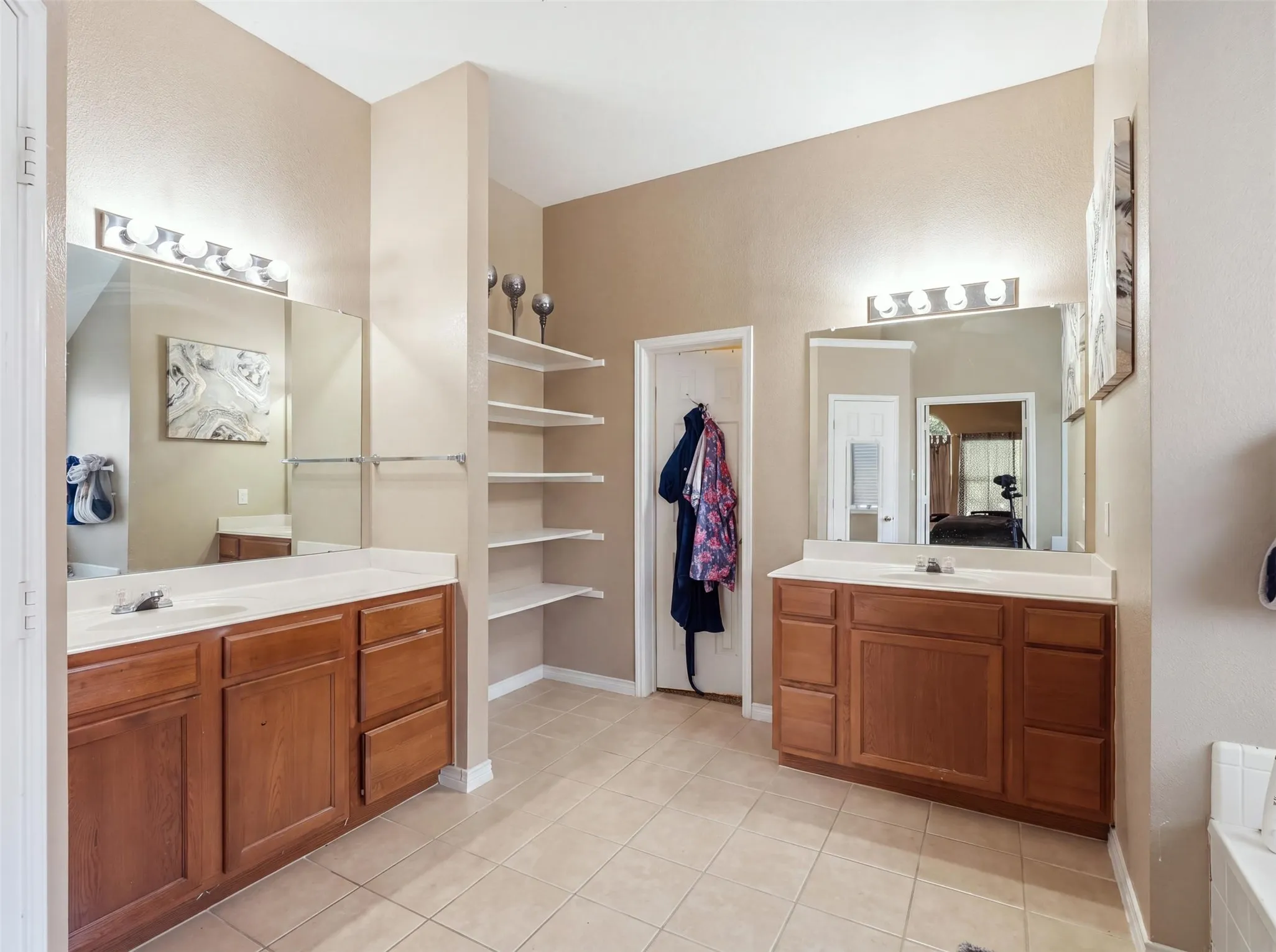 Dual vanity setup with wood-finish cabinetry, integrated sinks, and tiled flooring