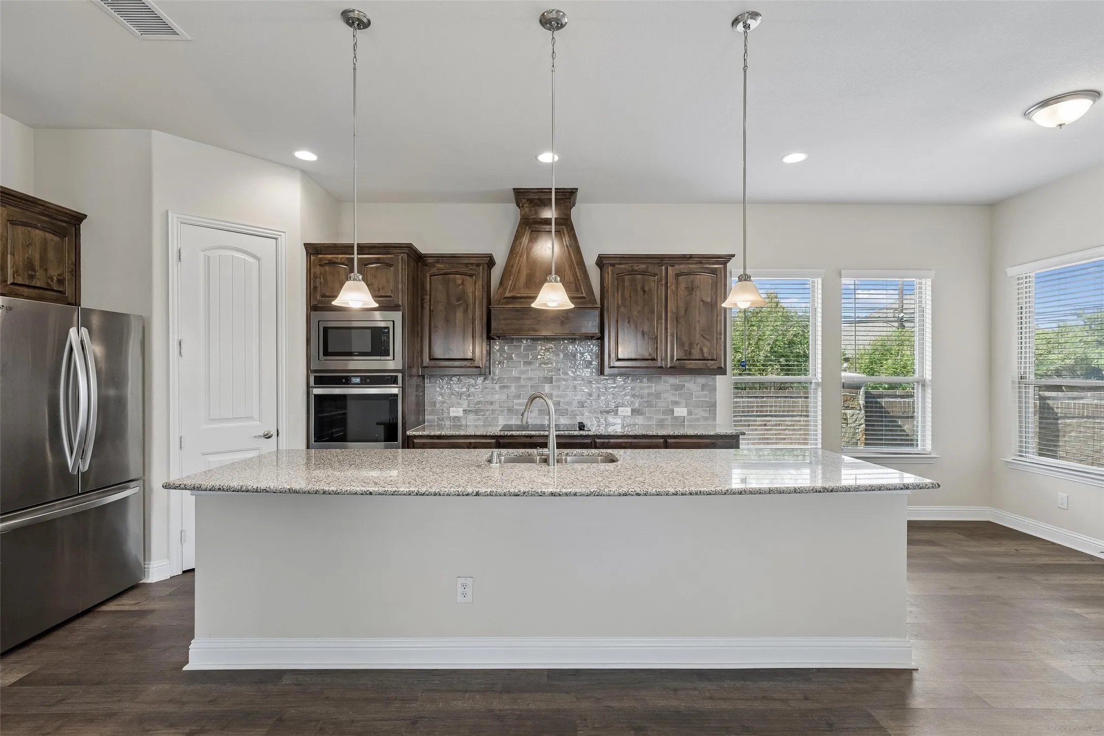 View of the kitchen and the eat in kitchen area. Featuring LVP flooring, plenty of natural light, range hood, double oven, extended cabinets and extended island.