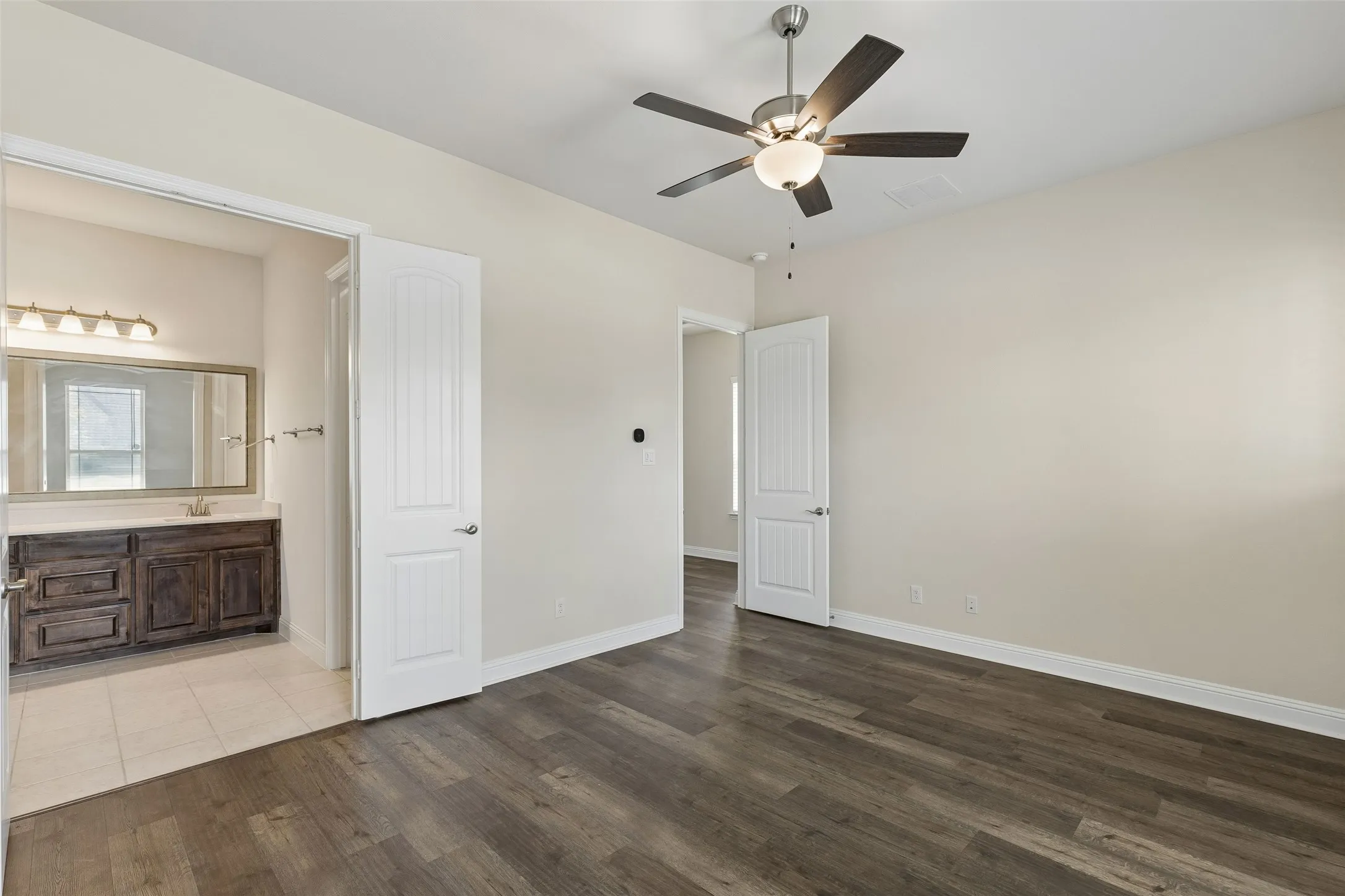 Primary bedroom featuring LVP flooring, high ceilings, plenty of natural light and an en suite bathroom.